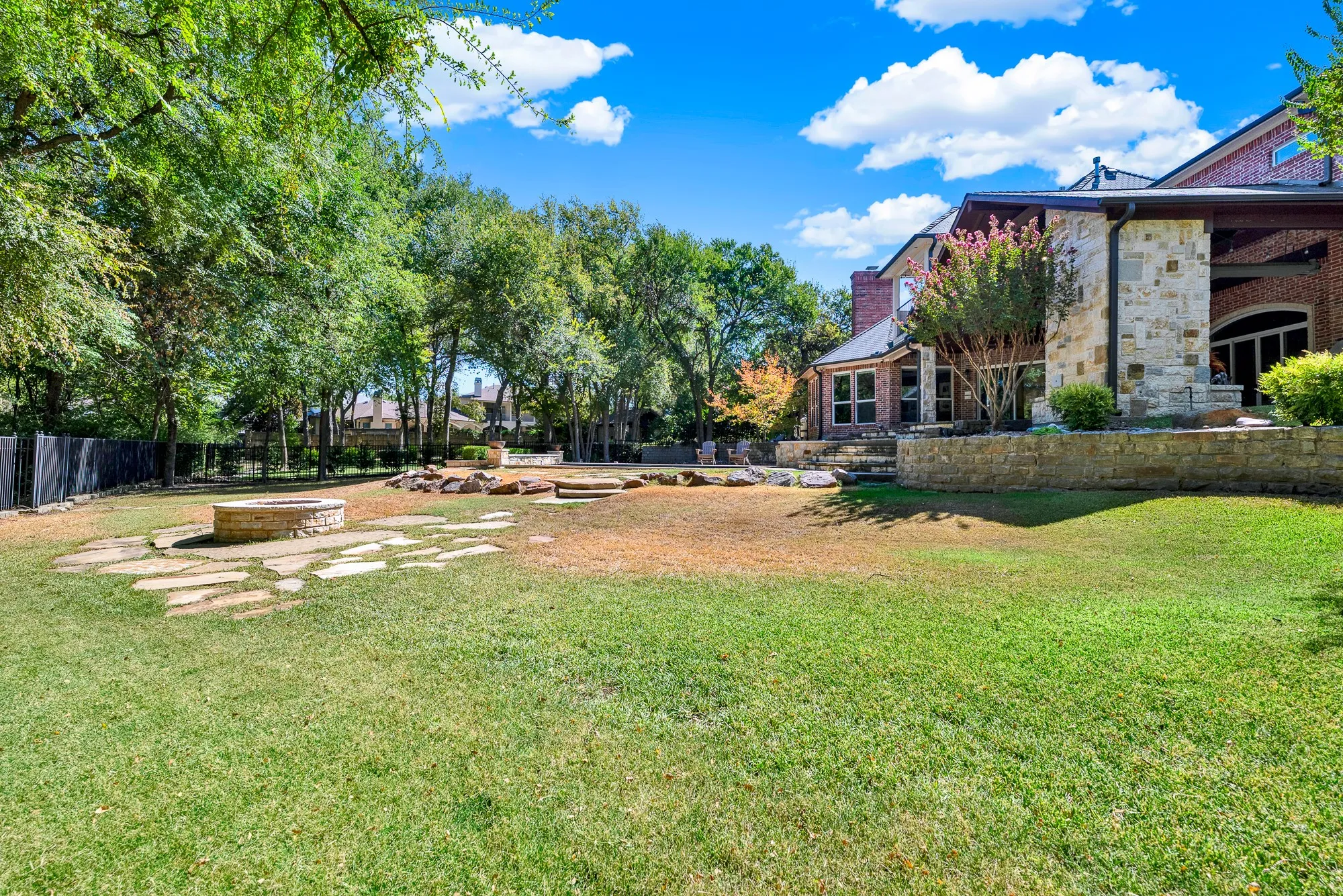 Flagstone pathways extend across the rolling backyard toward a dedicated stone fire pit ring. Unwind under clear night skies roasting marshmallows with family surrounded by quiet nature.
