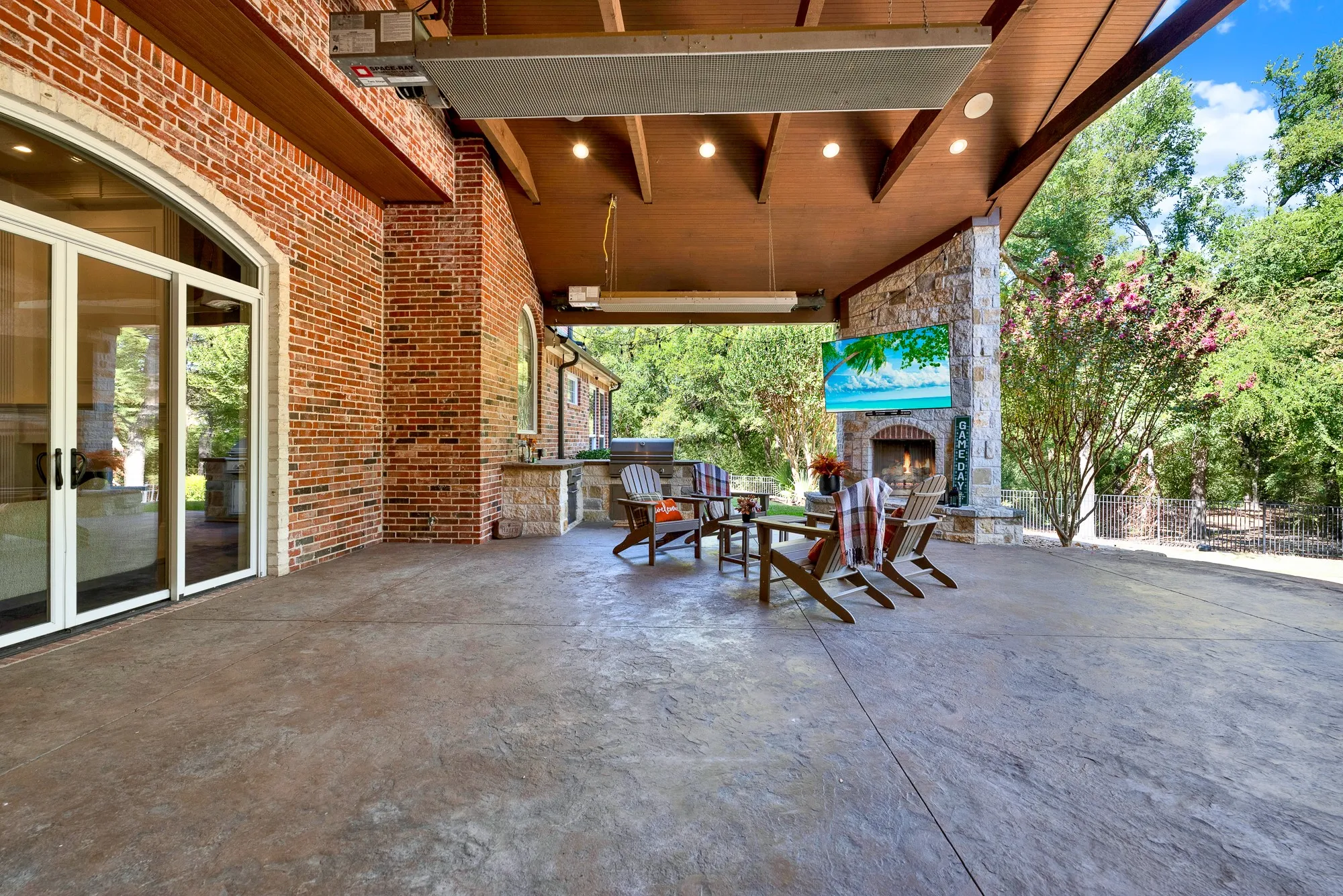 Wide glass sliding doors dissolve the boundary between rich interior brickwork and the vast covered stone patio. Host weekend game-day watch parties where guests seamlessly drift between indoor comforts and fresh open air.