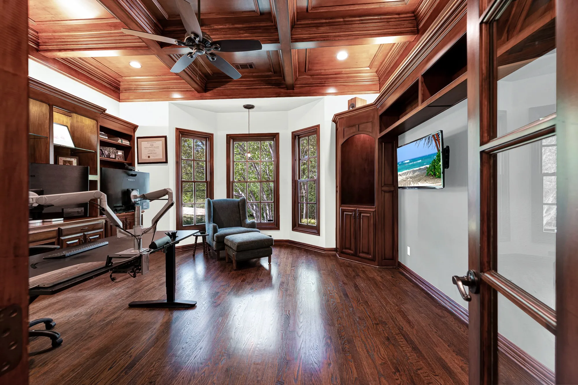 A rich coffered wood ceiling caps a sunlit bay window alcove framing tranquil treetop vistas. Spend a quiet morning reflecting in natural light before starting your day