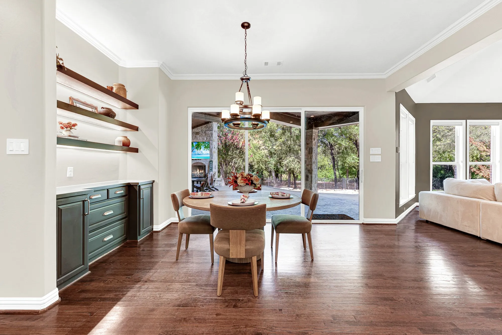 A built-in sideboard niche with warm floating shelves anchors the space against a wall of sliding glass doors. Morning sunlight streams across the rich wood floors as you brew your favorite roast.