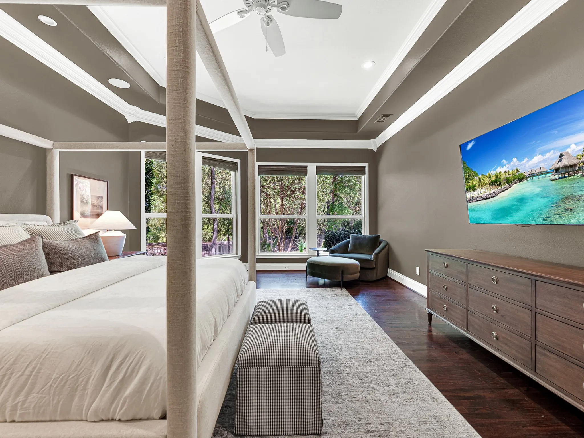 Crisp white baseboards offset warm wall tones that wrap seamlessly into an adjacent private hallway. Enjoy a serene evening retreat watching your favorite show before drifting off to sleep.