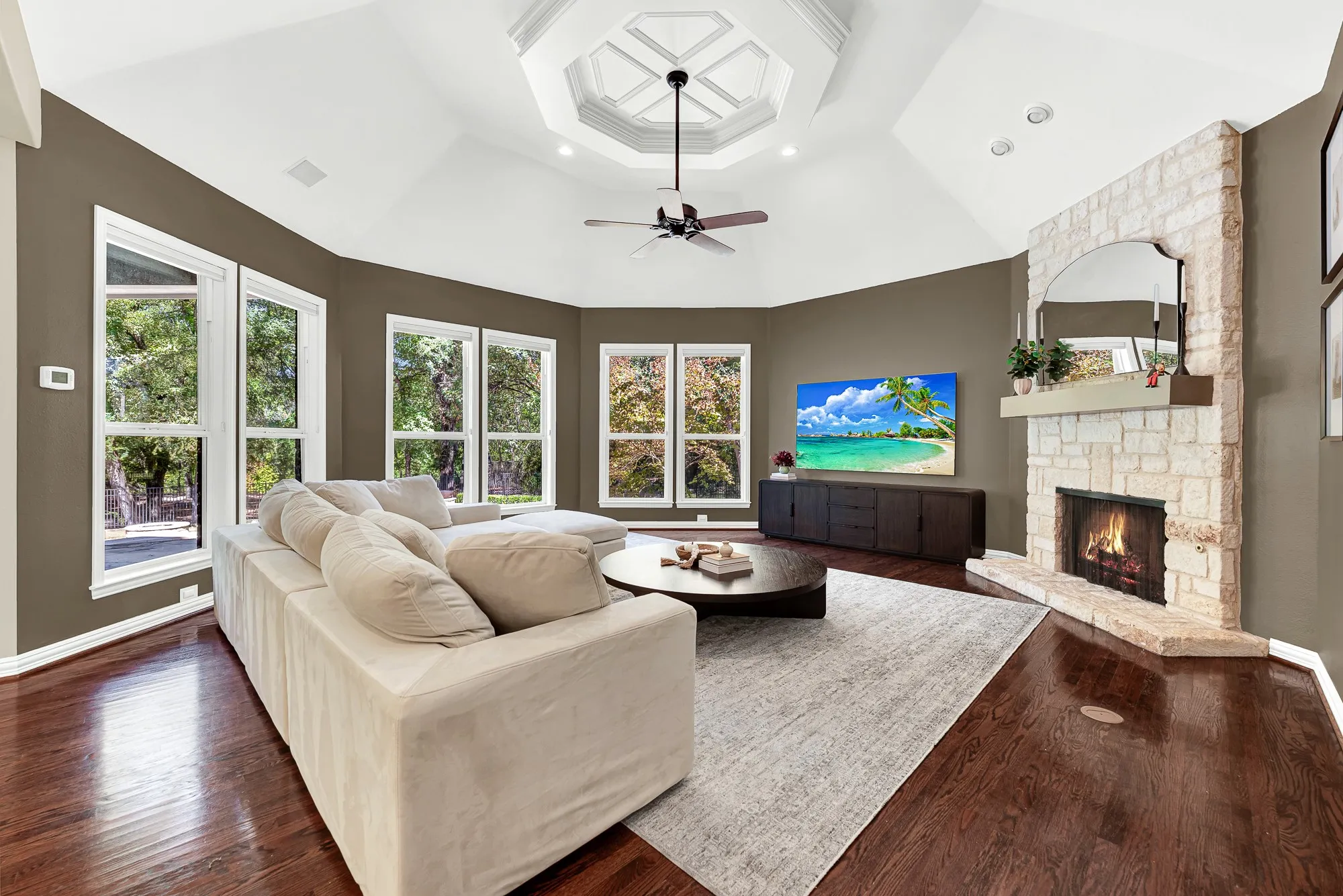 A rustic stone fireplace hearth rises to meet the soaring vaulted ceiling's detailed inset tray. Picture curling up here with a cozy blanket as flames dance on a chilly winter evening.