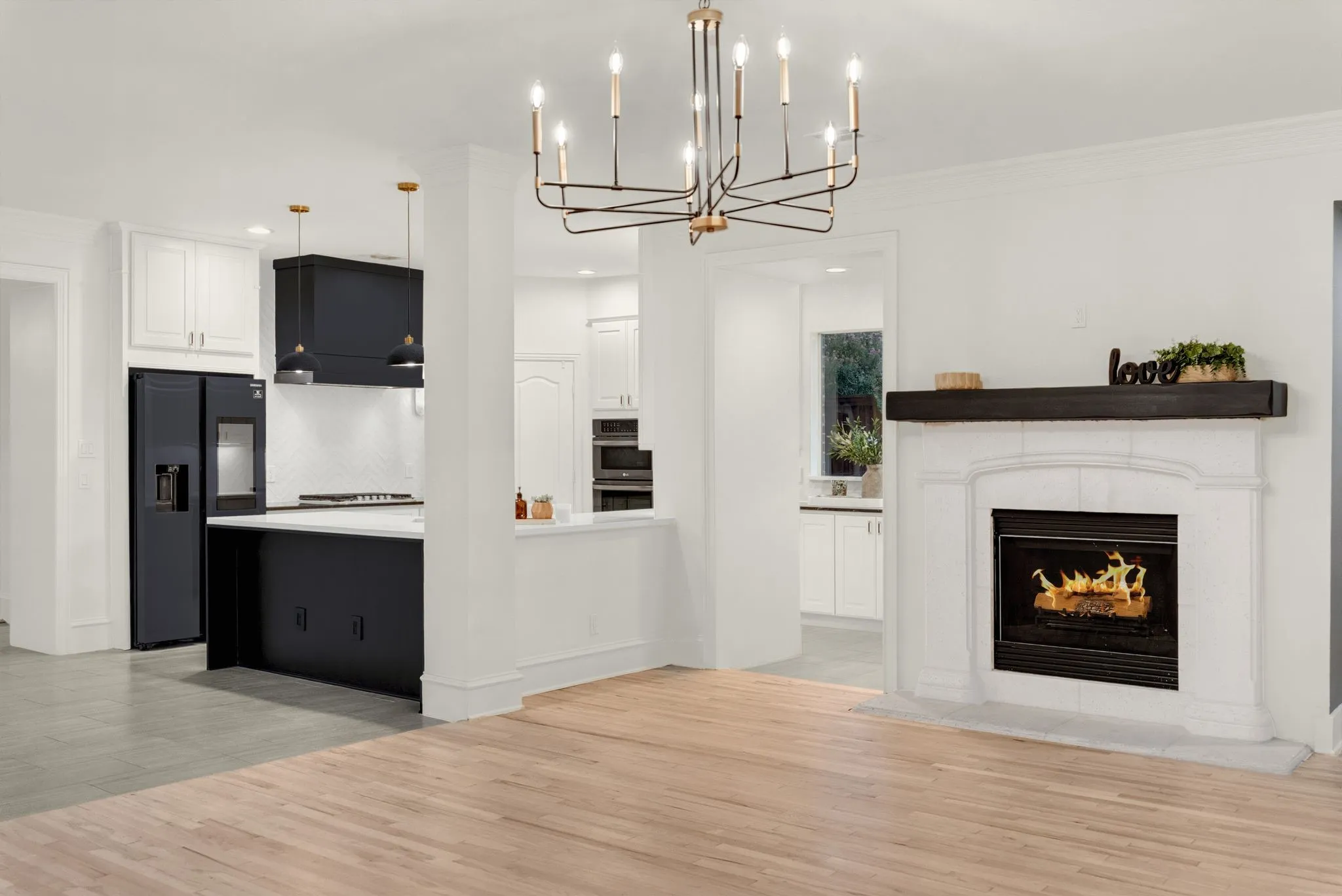 Modern open-concept kitchen and living space featuring a black and white cabinetry design with stainless steel appliances, white subway tile backsplash, and wood-finish flooring