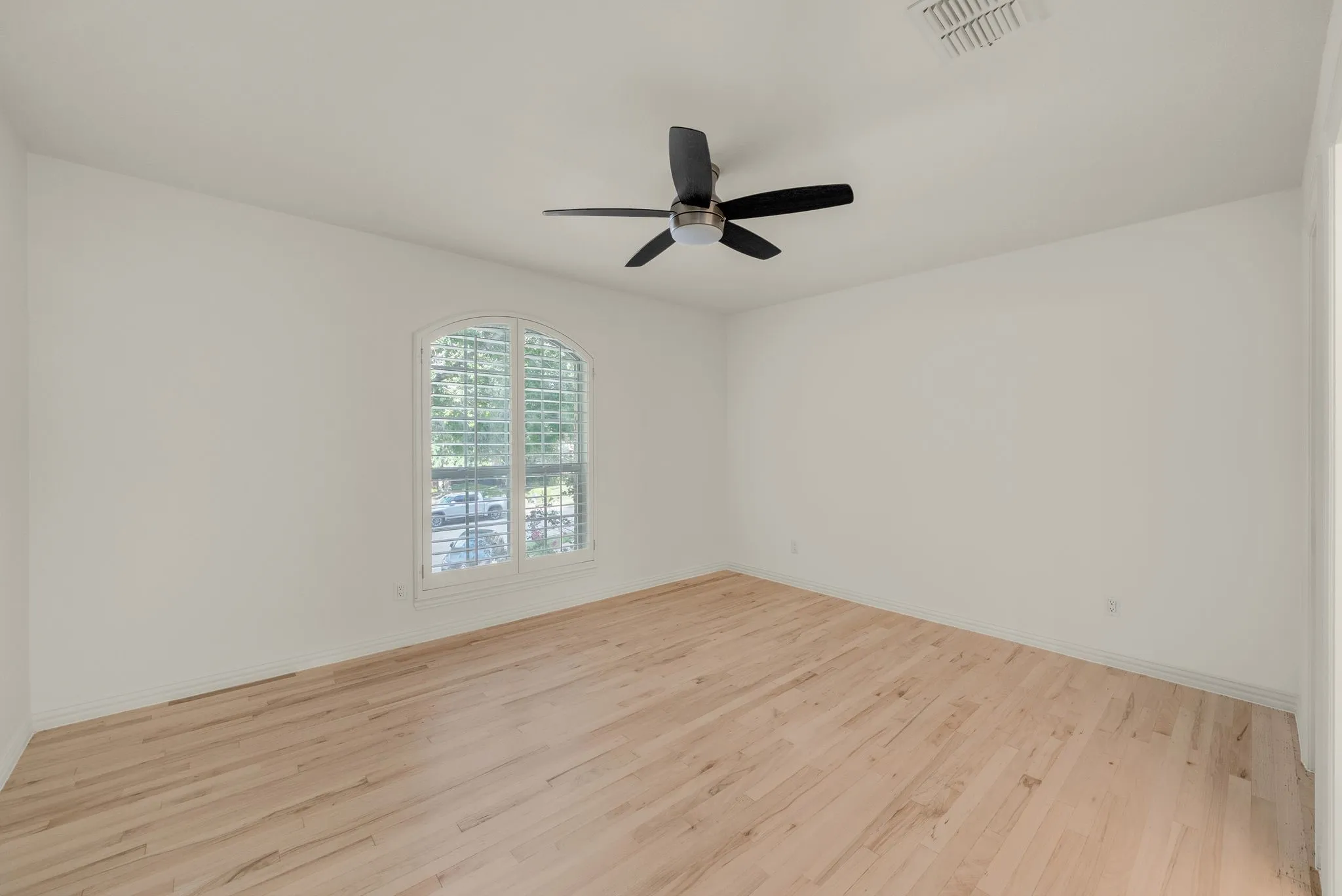 Arched window with plantation shutters, light wood-finish flooring, ceiling fan, and recessed lighting