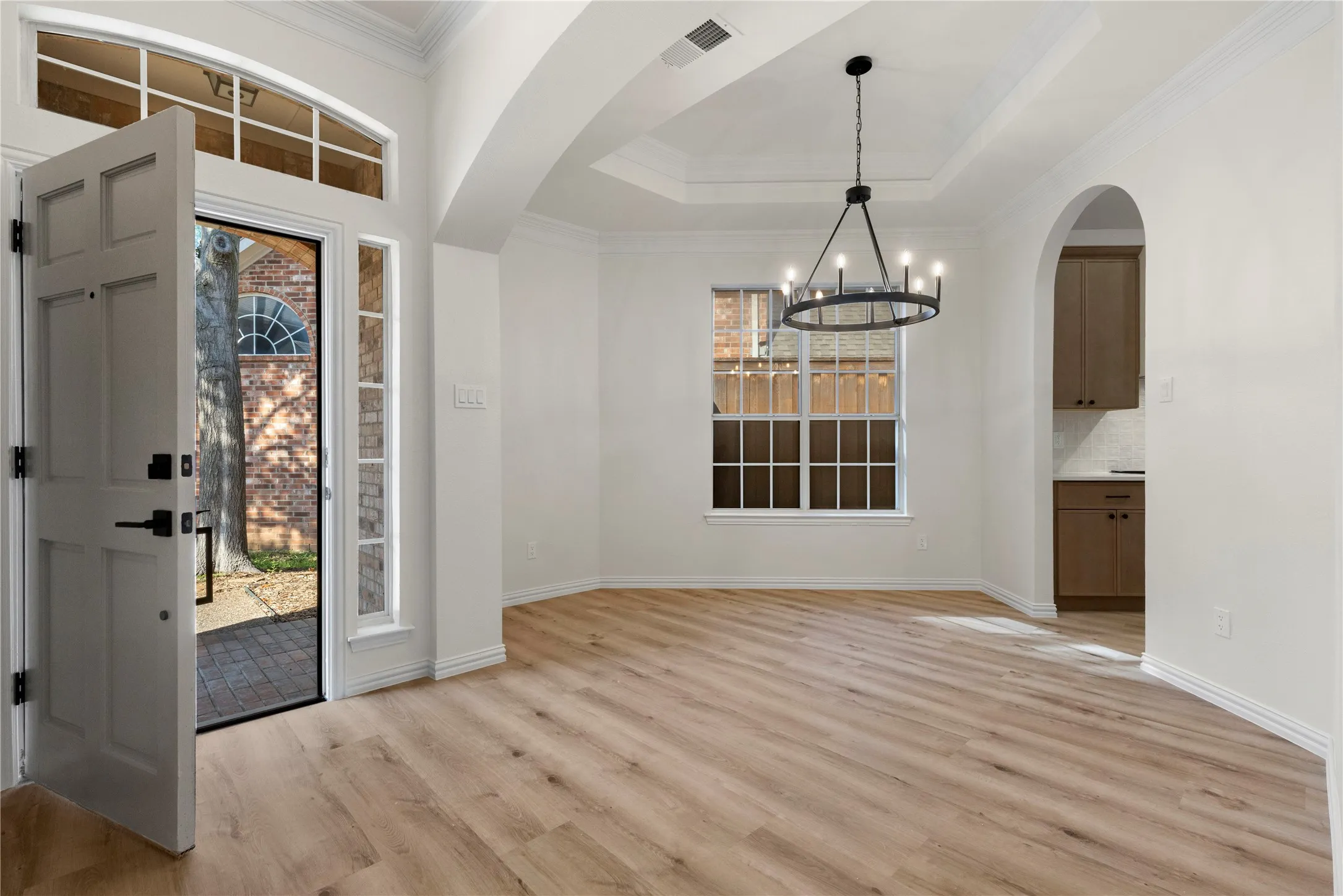 Entryway featuring wood-finish flooring, a tray ceiling, and a black chandelier