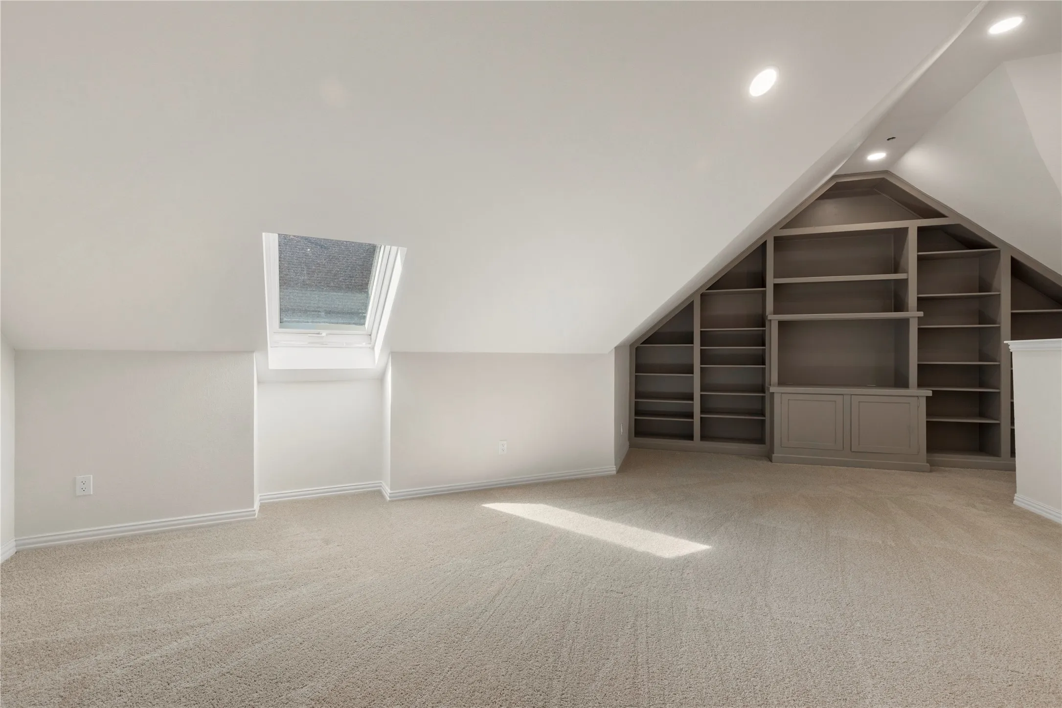 Sloped ceilings with recessed lighting, built-in shelving, integrated cabinetry, and a skylight
