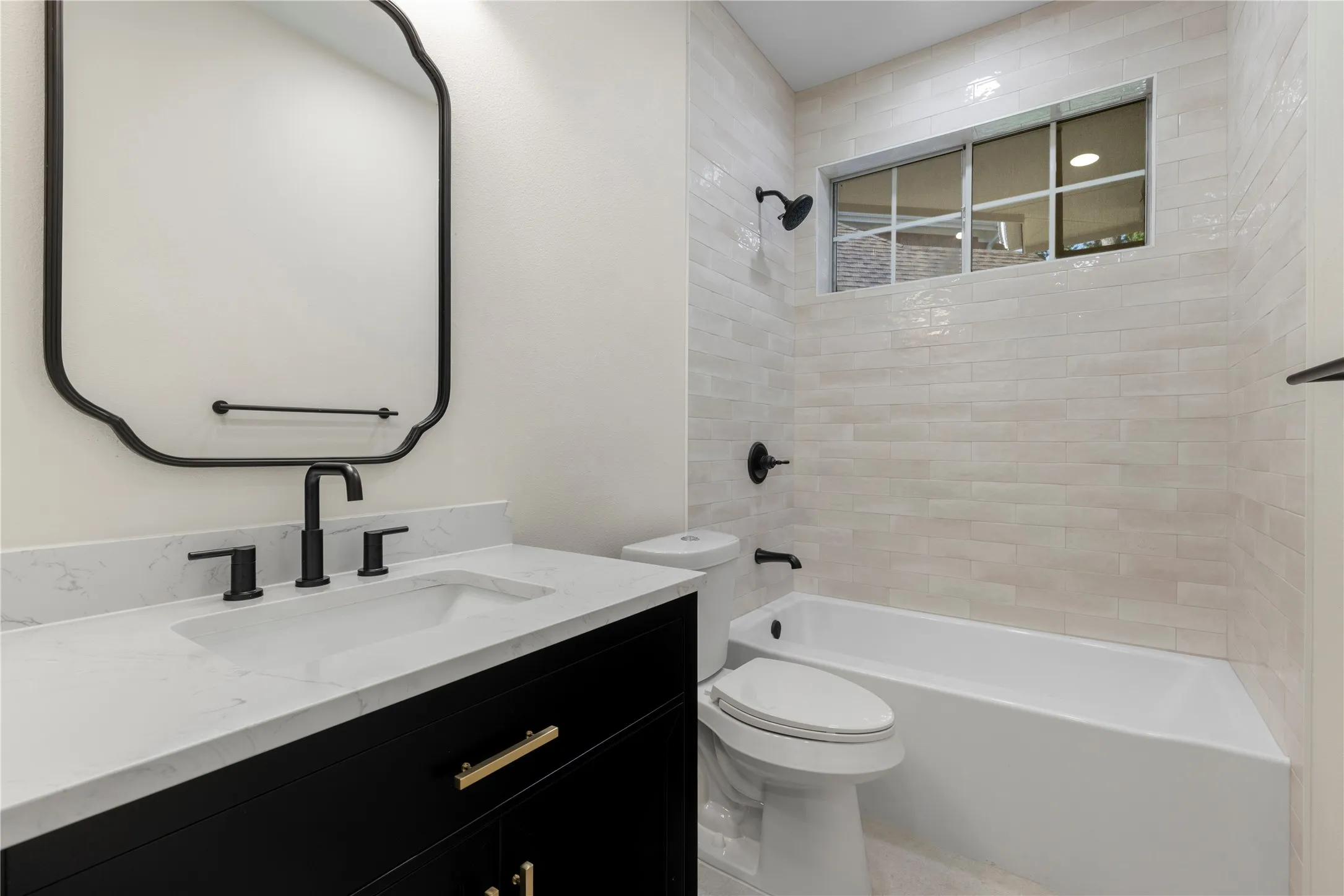 Bathroom featuring a white bathtub, toilet, vanity with a white countertop, under-mount sink, and dark-finish fixtures