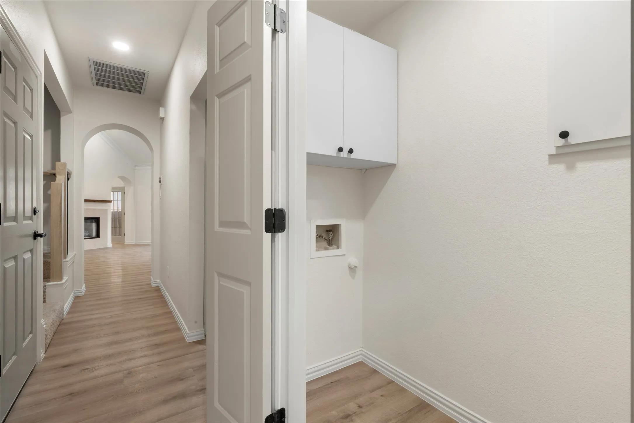 Utility space featuring overhead cabinetry and wood-finish flooring
