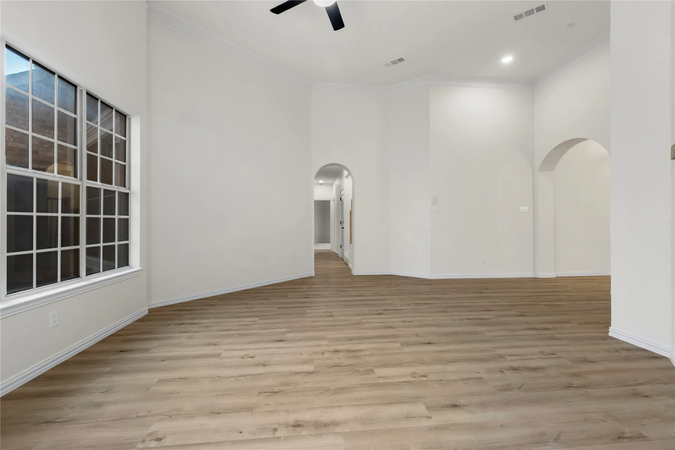 Vaulted ceiling, wood-finish flooring, architectural archways, recessed lighting, and a ceiling fan
