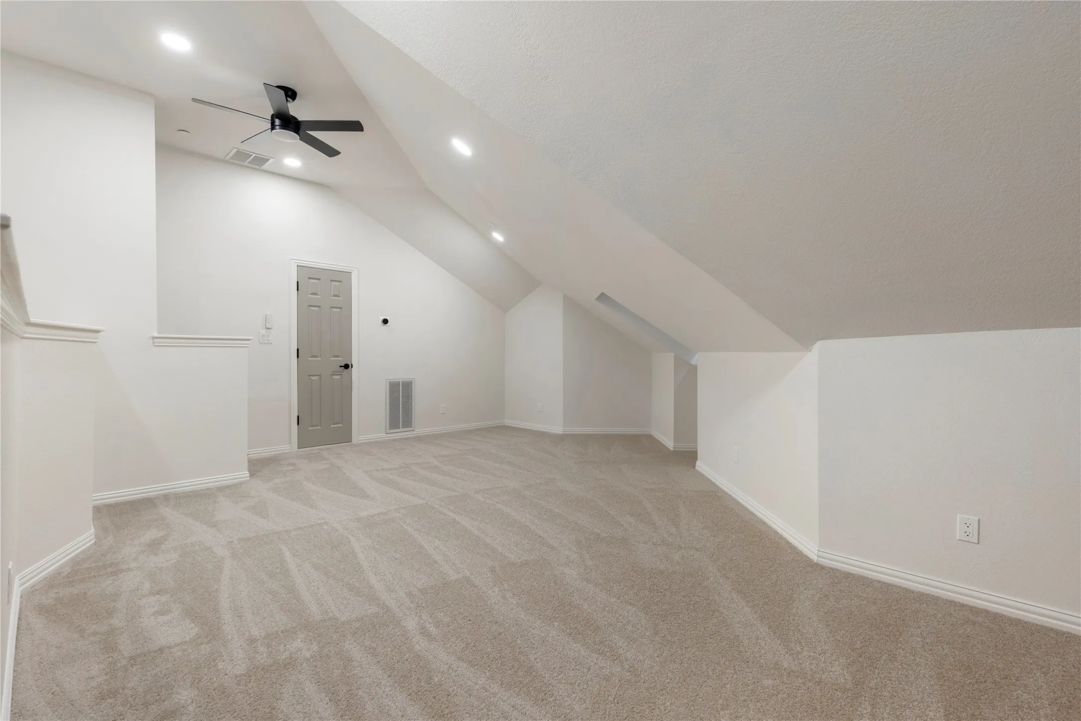 Spacious vaulted ceiling room with recessed lighting and a ceiling fan, featuring light-colored carpet flooring and a neutral color palette