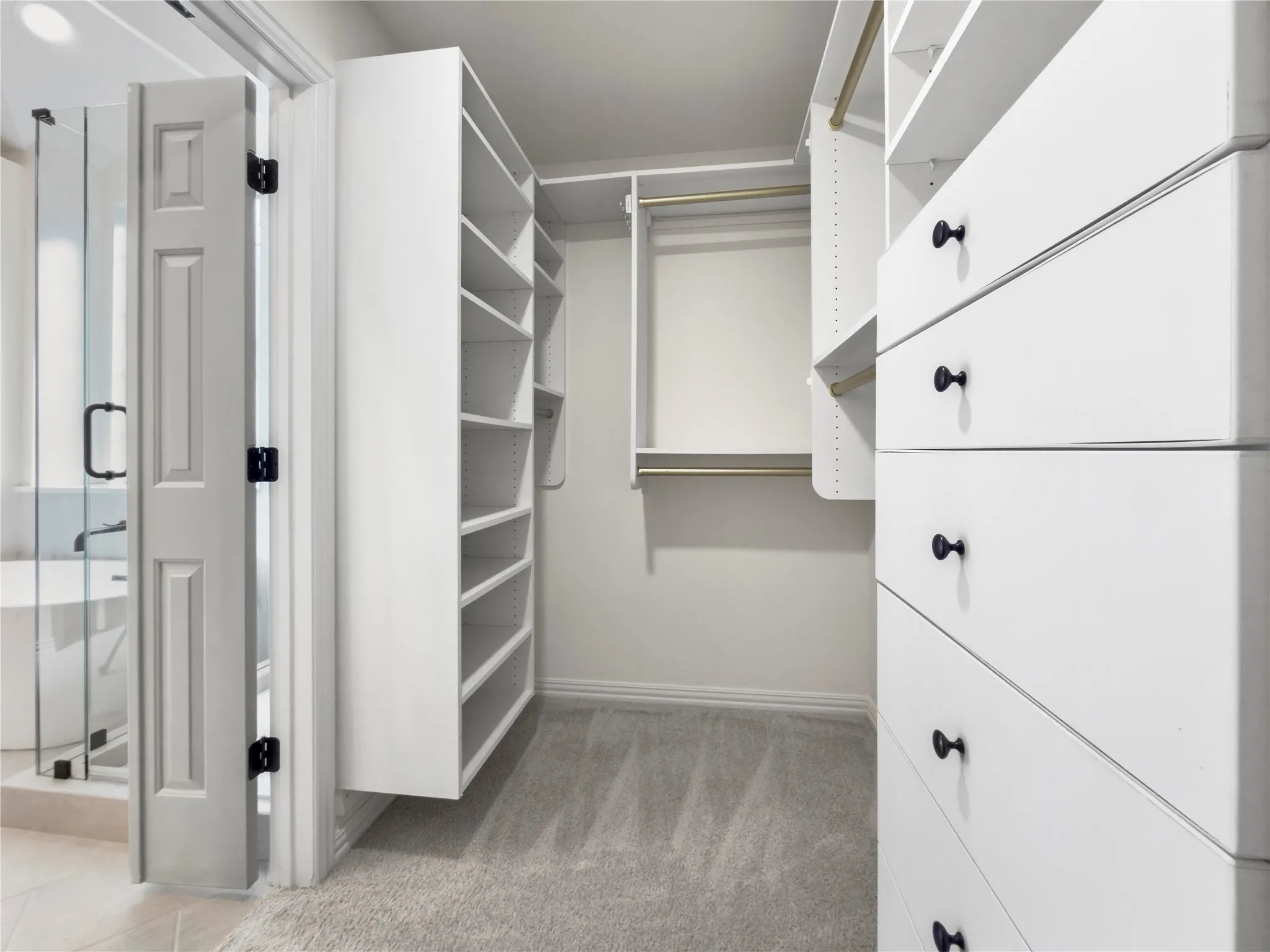 Custom closet system featuring built-in shelving, multiple drawers with dark hardware, and hanging rods