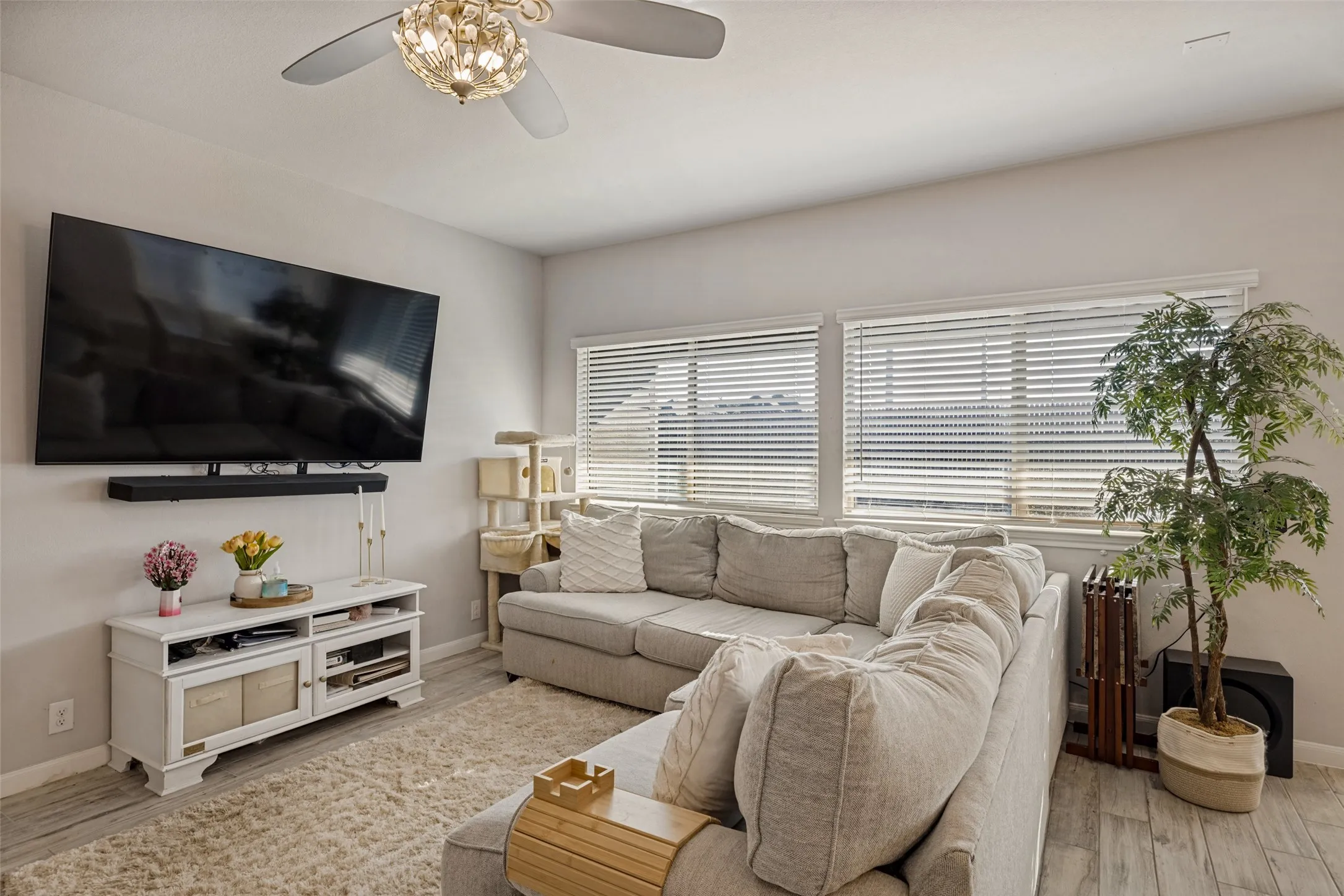 Recessed lighting, wood-finish flooring, two large windows with blinds, and a decorative ceiling fan