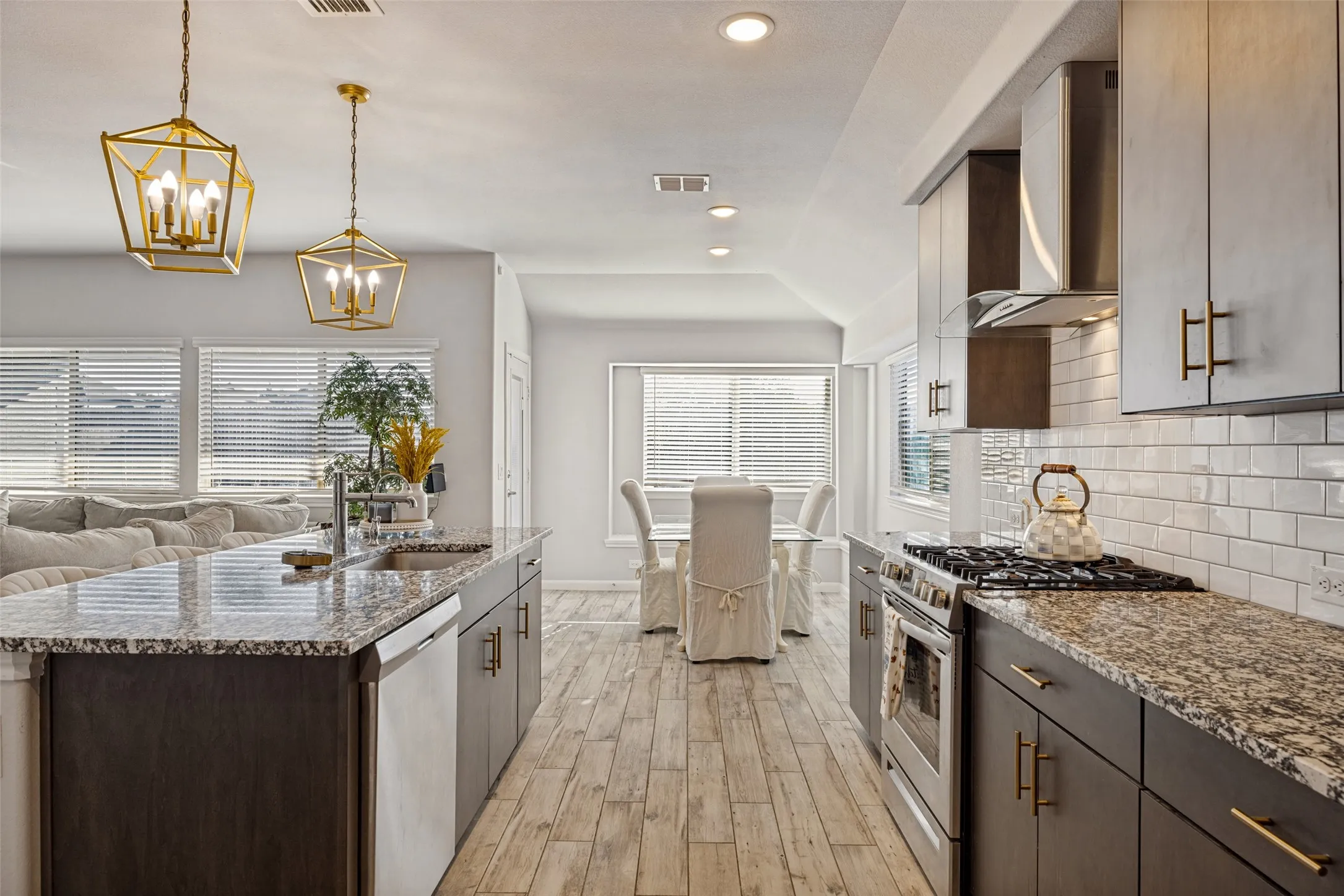 Kitchen featuring granite countertops, stainless steel appliances, white subway tile backsplash, recessed lighting, and wood-look flooring