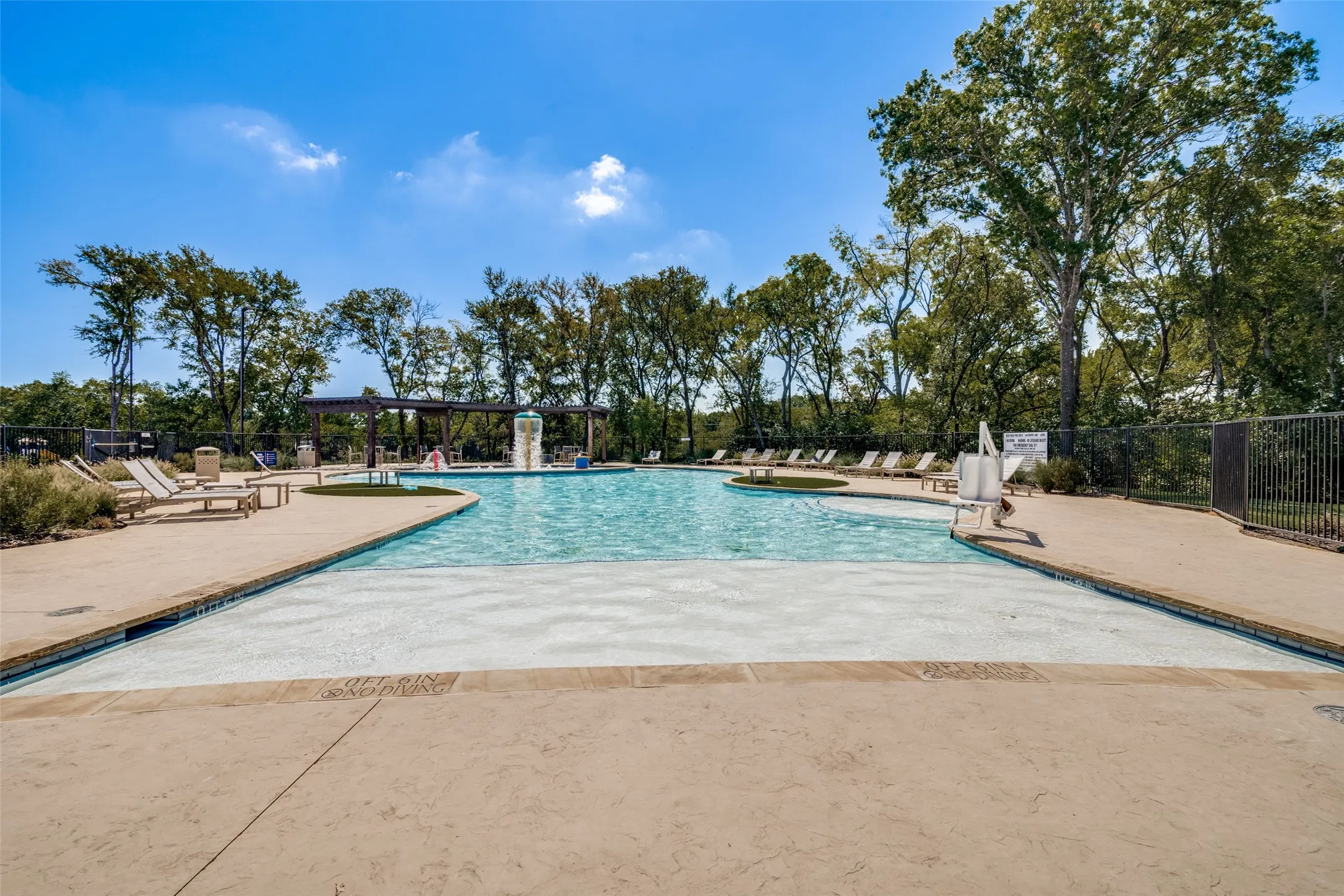 Expansive outdoor pool with integrated water feature, surrounded by a paved deck and mature trees