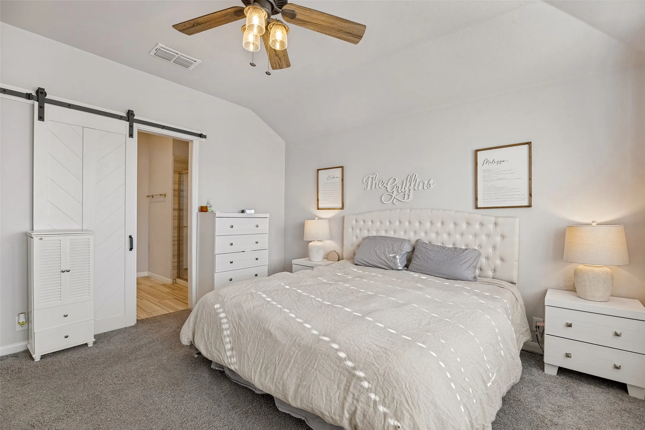 Vaulted ceiling with a ceiling fan, white barn door with chevron detailing, and light gray wall paint