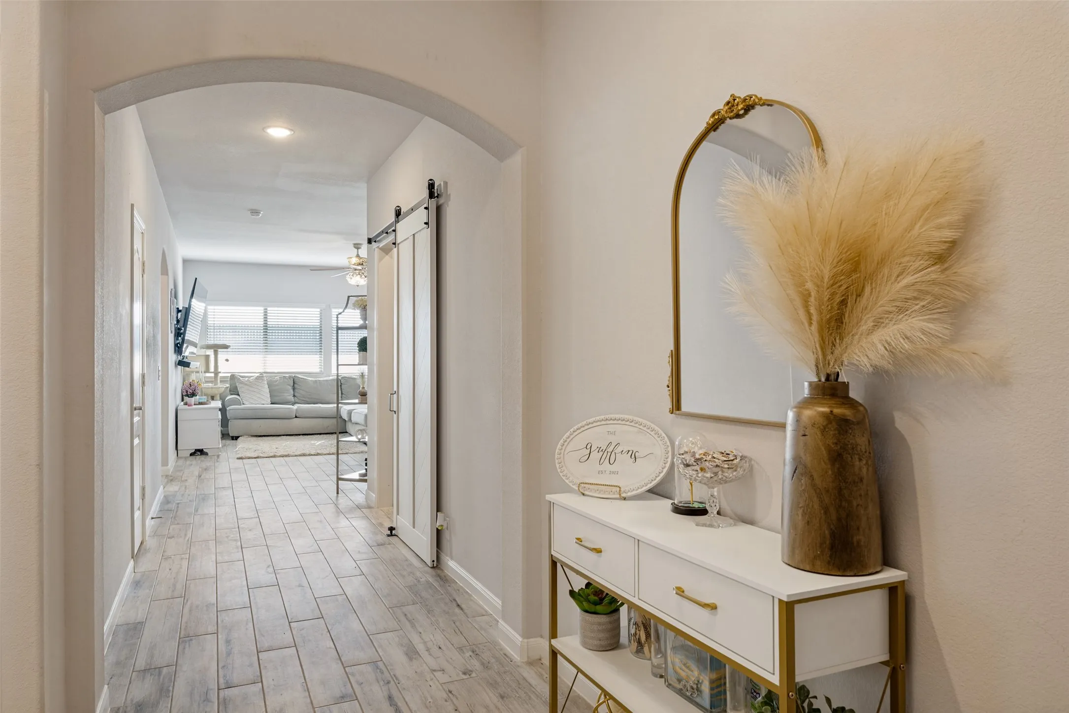 Arched entryway leading to a living area with wood-finish flooring, a barn door, and recessed lighting