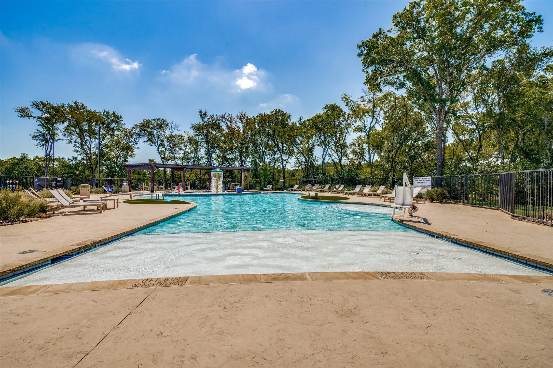 Expansive community pool featuring a multi-level design, integrated water feature, and a surrounding patio