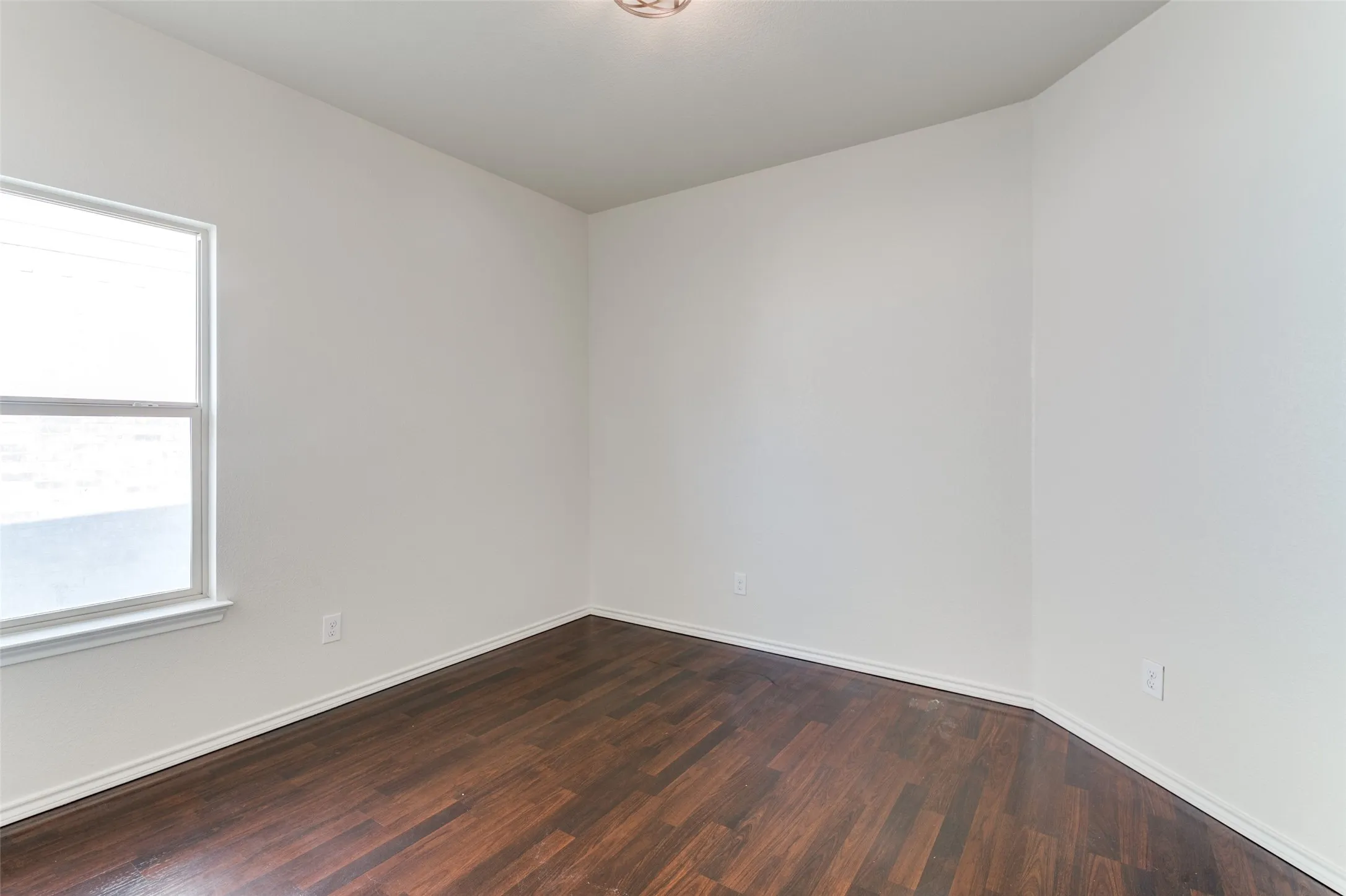 Spare room with dark wood-style floors and baseboards