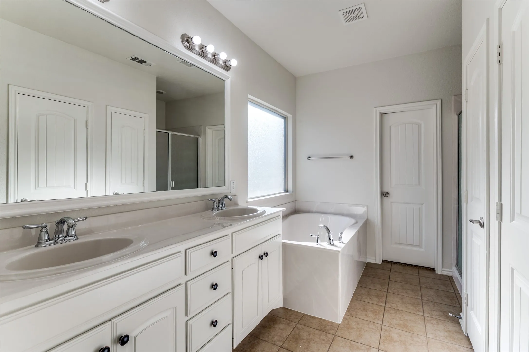 Bathroom featuring a stall shower, double vanity, a garden tub, and tile patterned flooring