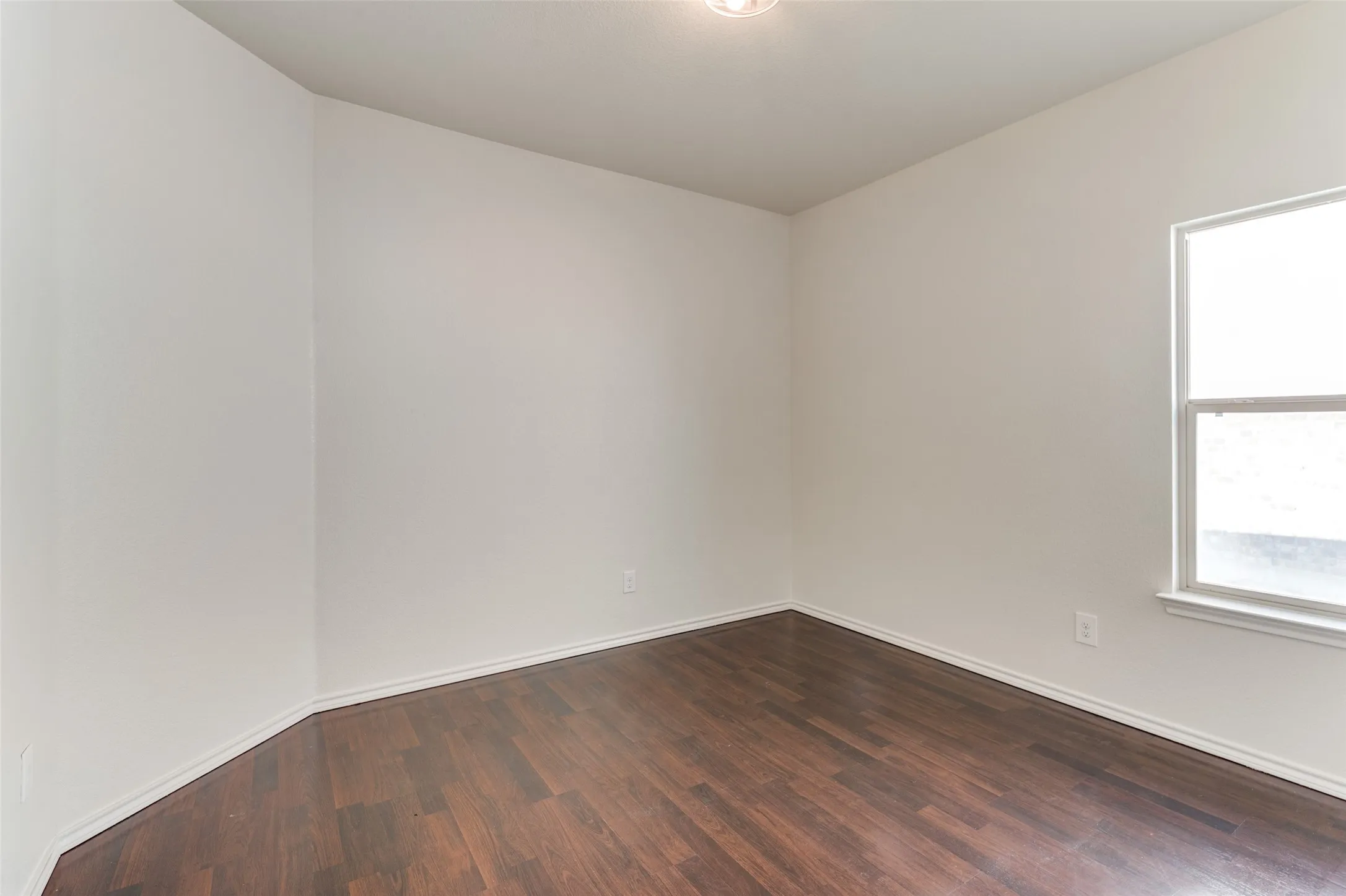 Empty room with dark wood-style floors and baseboards