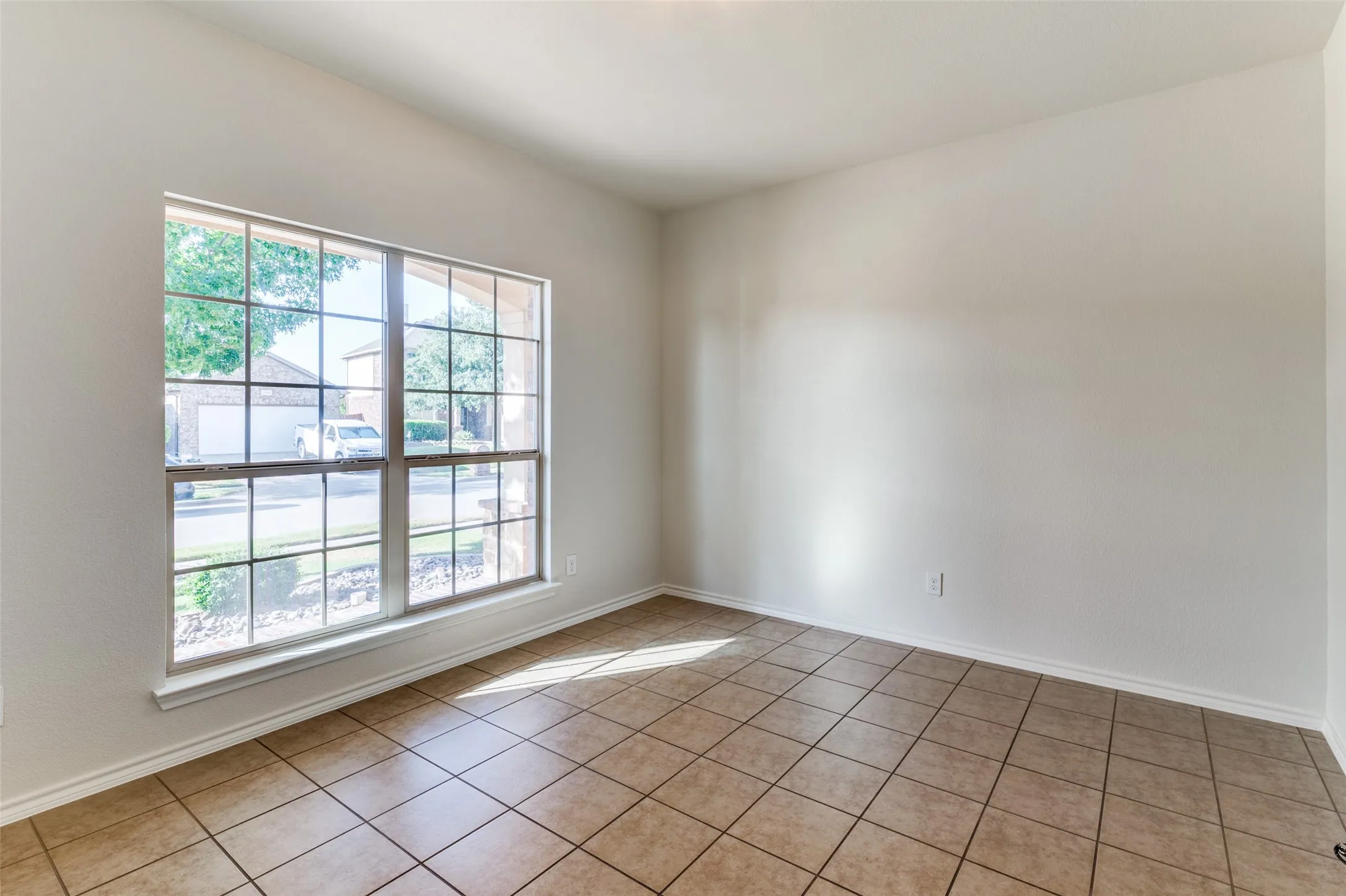Empty room featuring light tile patterned flooring and baseboards