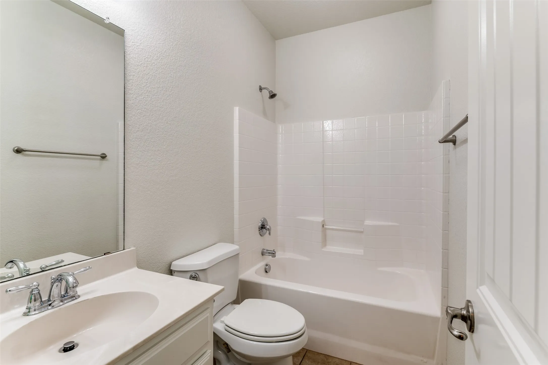 Full bath with vanity, a textured wall, and bathtub / shower combination