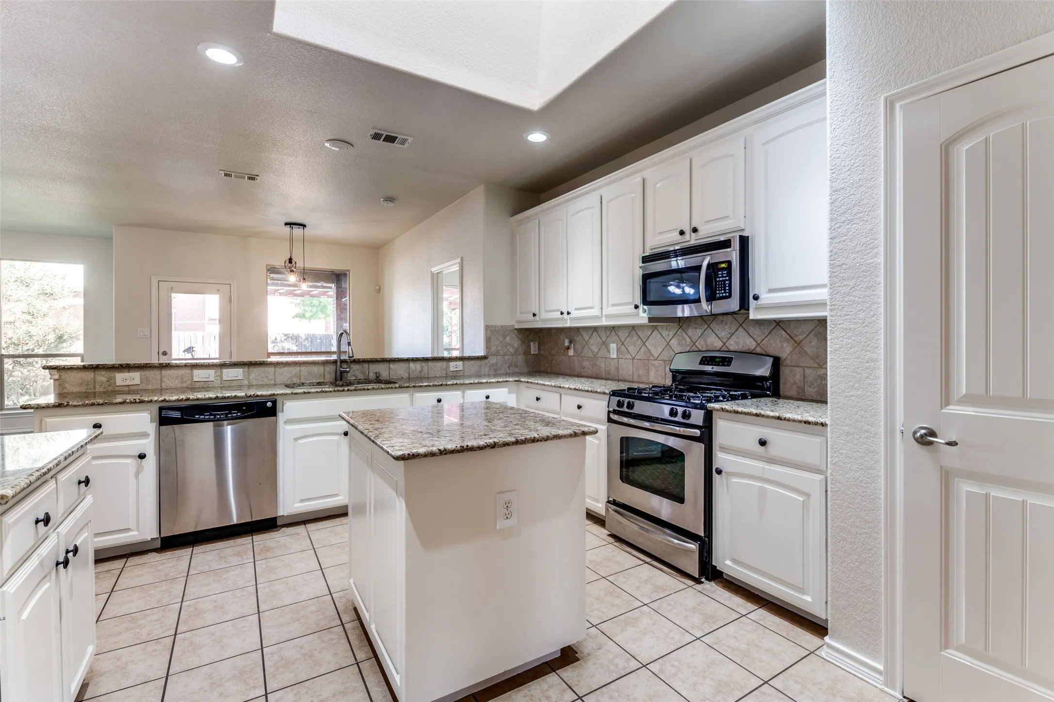 Kitchen featuring appliances with stainless steel finishes, recessed lighting, a peninsula, tasteful backsplash, and white cabinetry