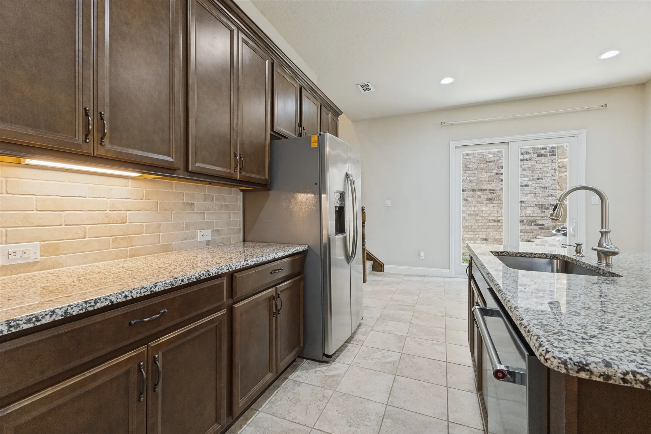 Rich wood-finish cabinetry, granite countertops, subway tiled backsplash
