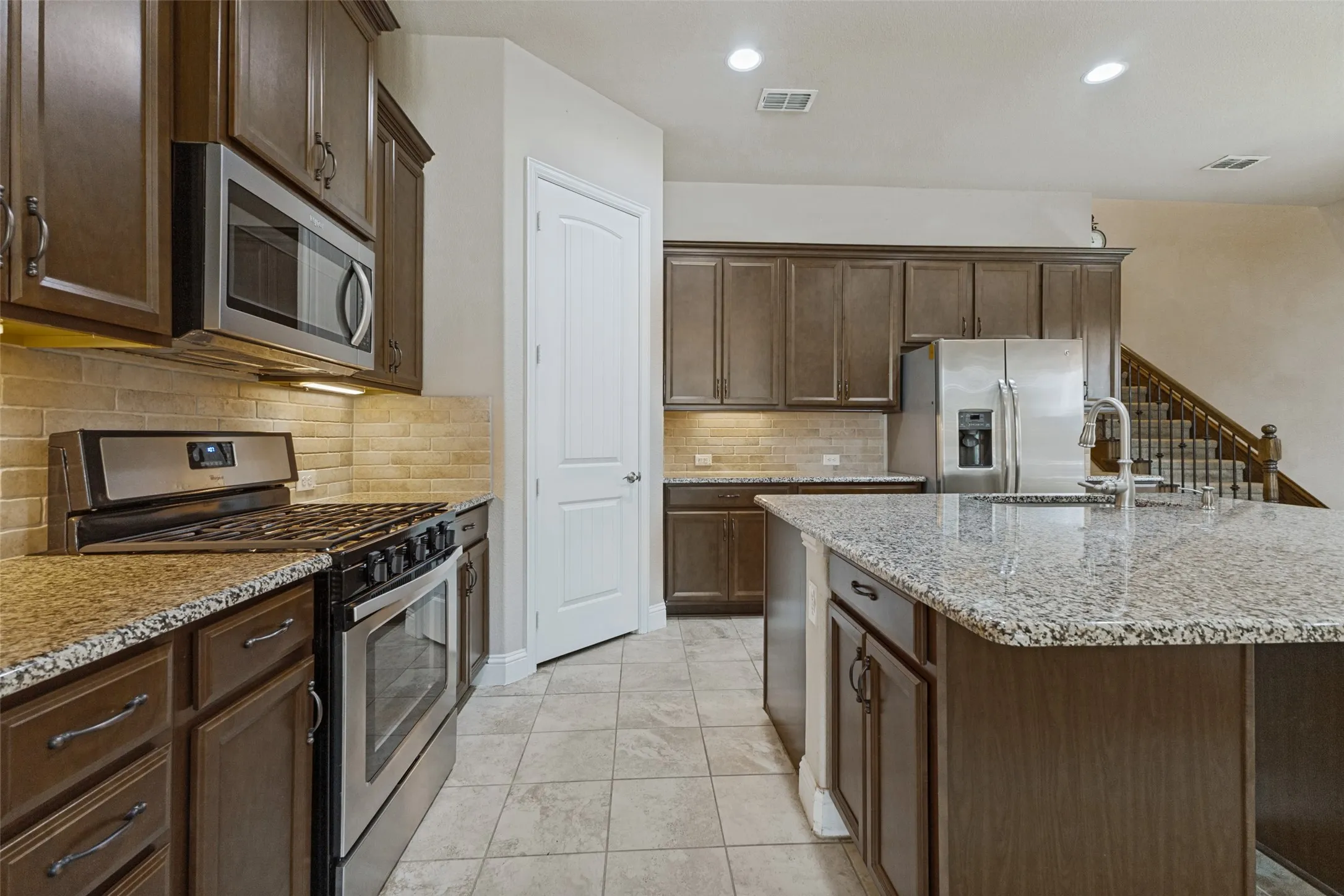 Kitchen featuring gas cooktop range, built-in microwave, extensive cabinetry and tile flooring
