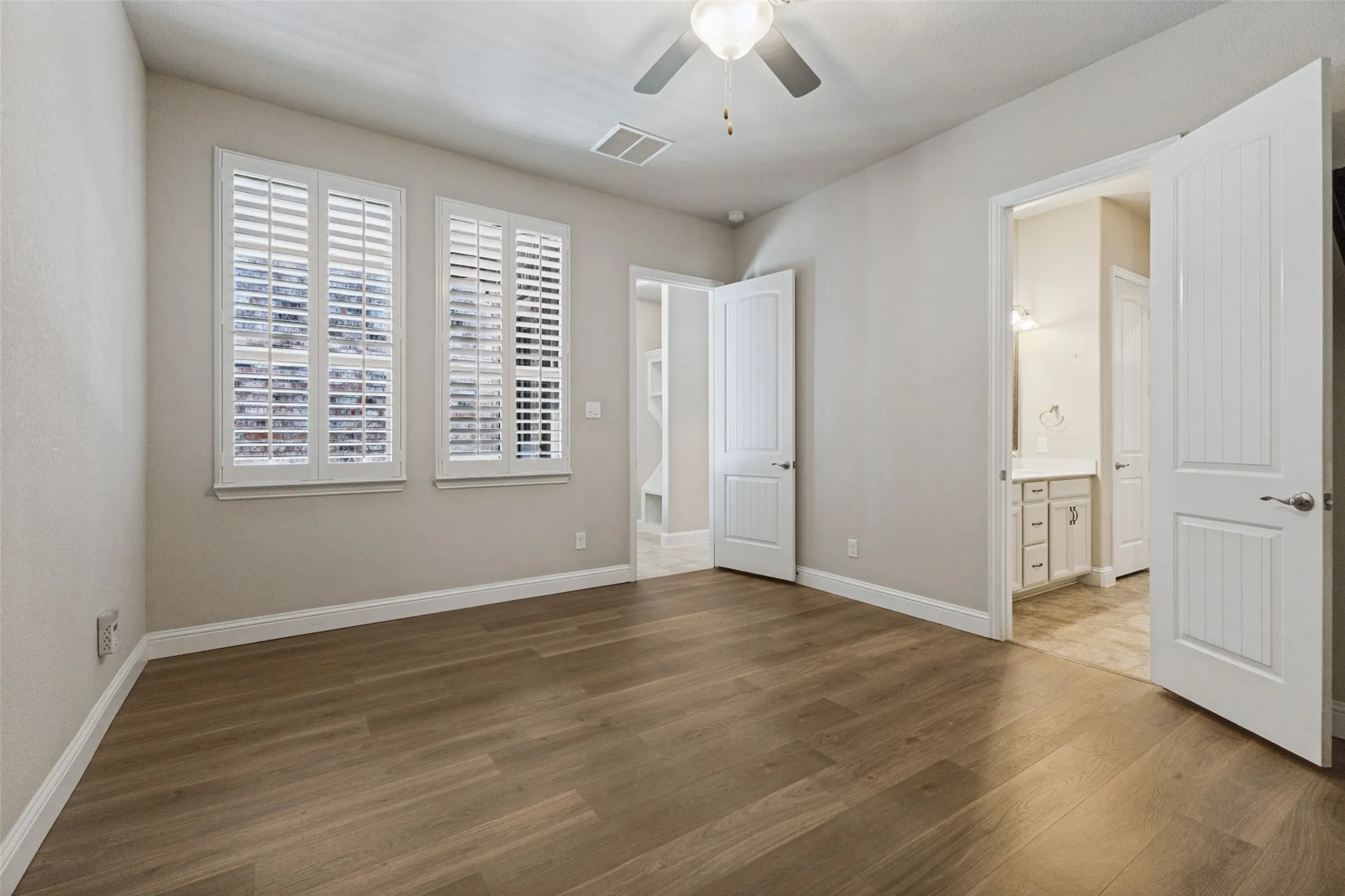 Wood flooring, plantation shutters, ceiling fan, and 8 ft paneled doors