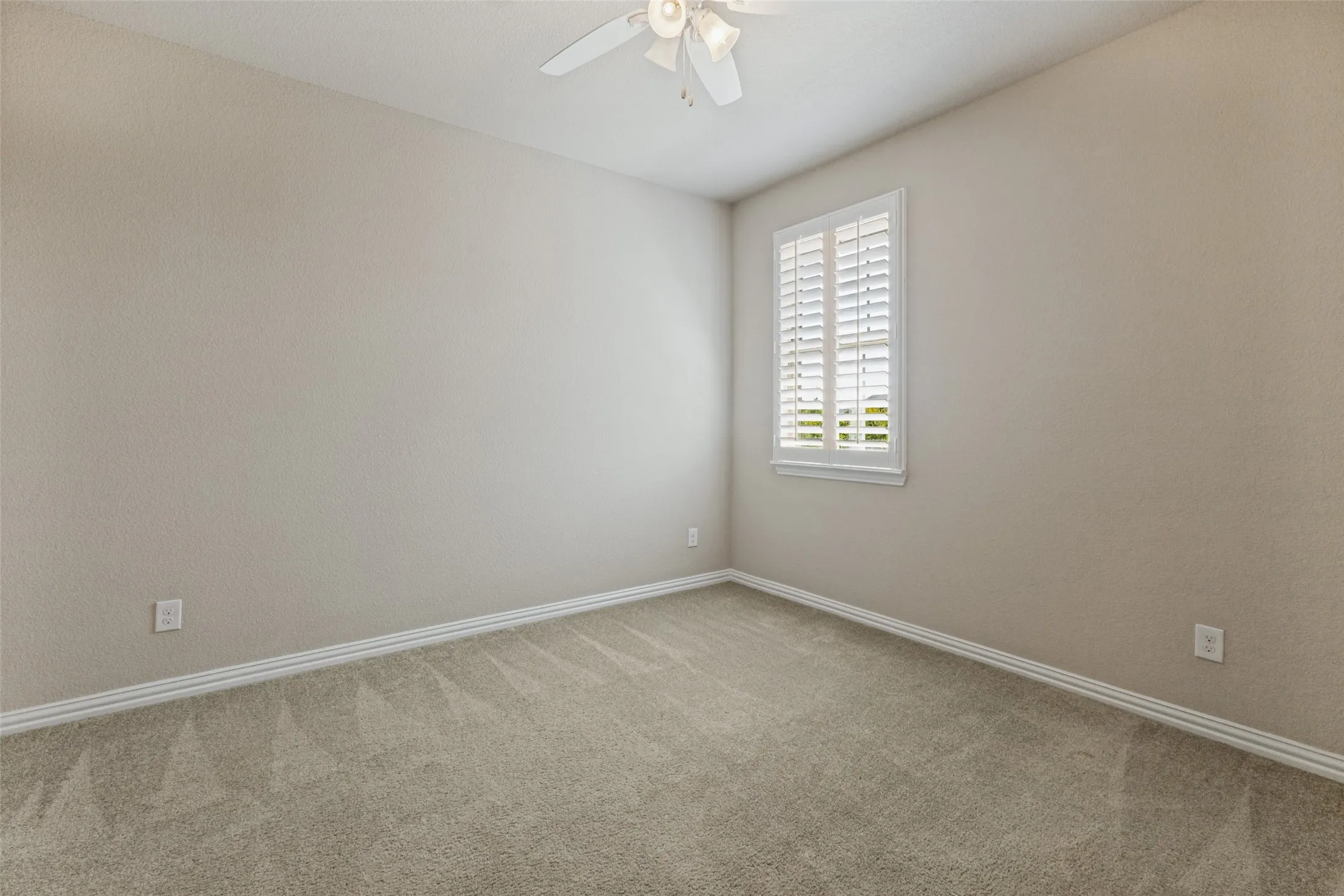 Second upstairs bedroom with ceiling fan and plantation shutters