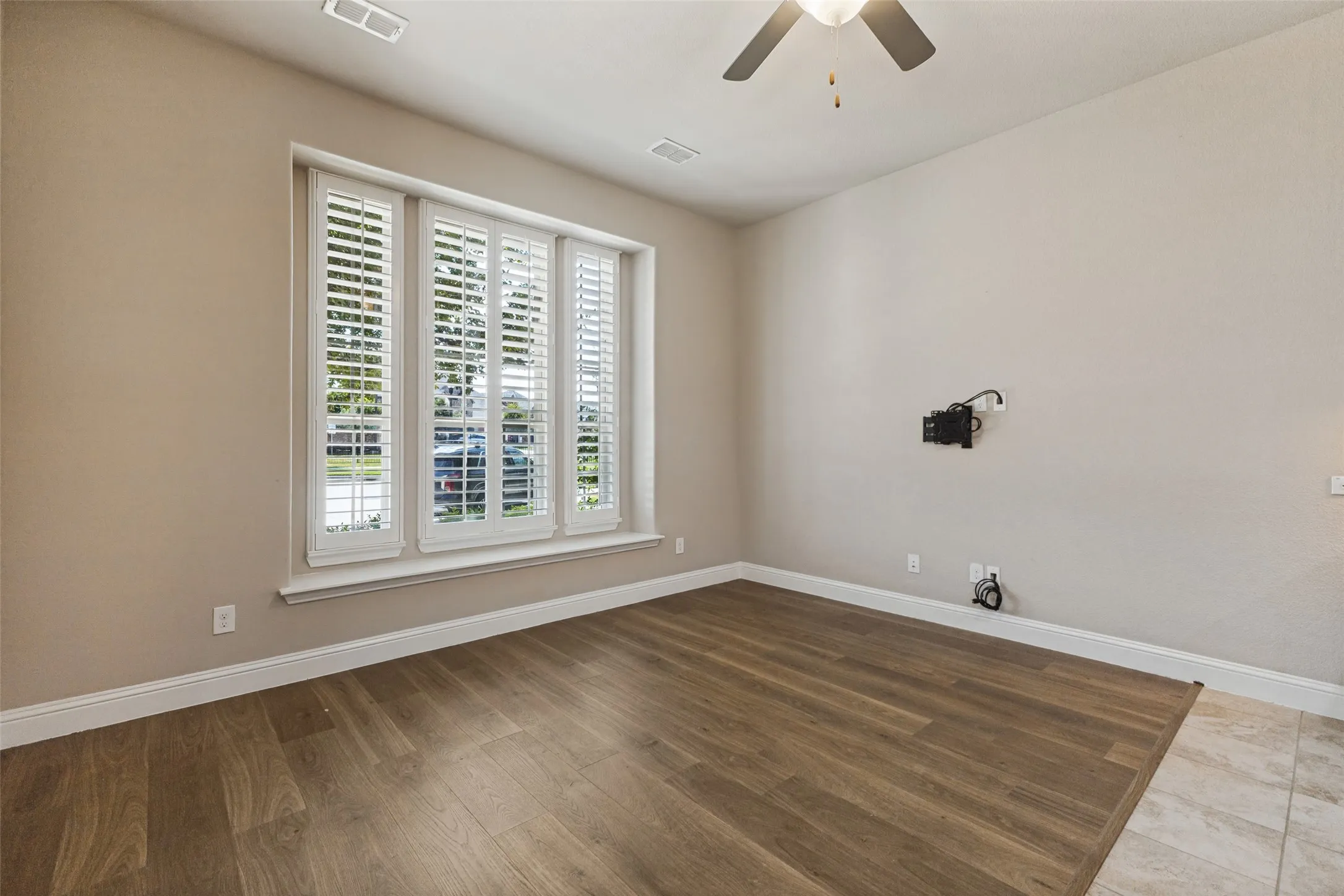Wood flooring, plantation shutters, ceiling fan, and neutral wall tones