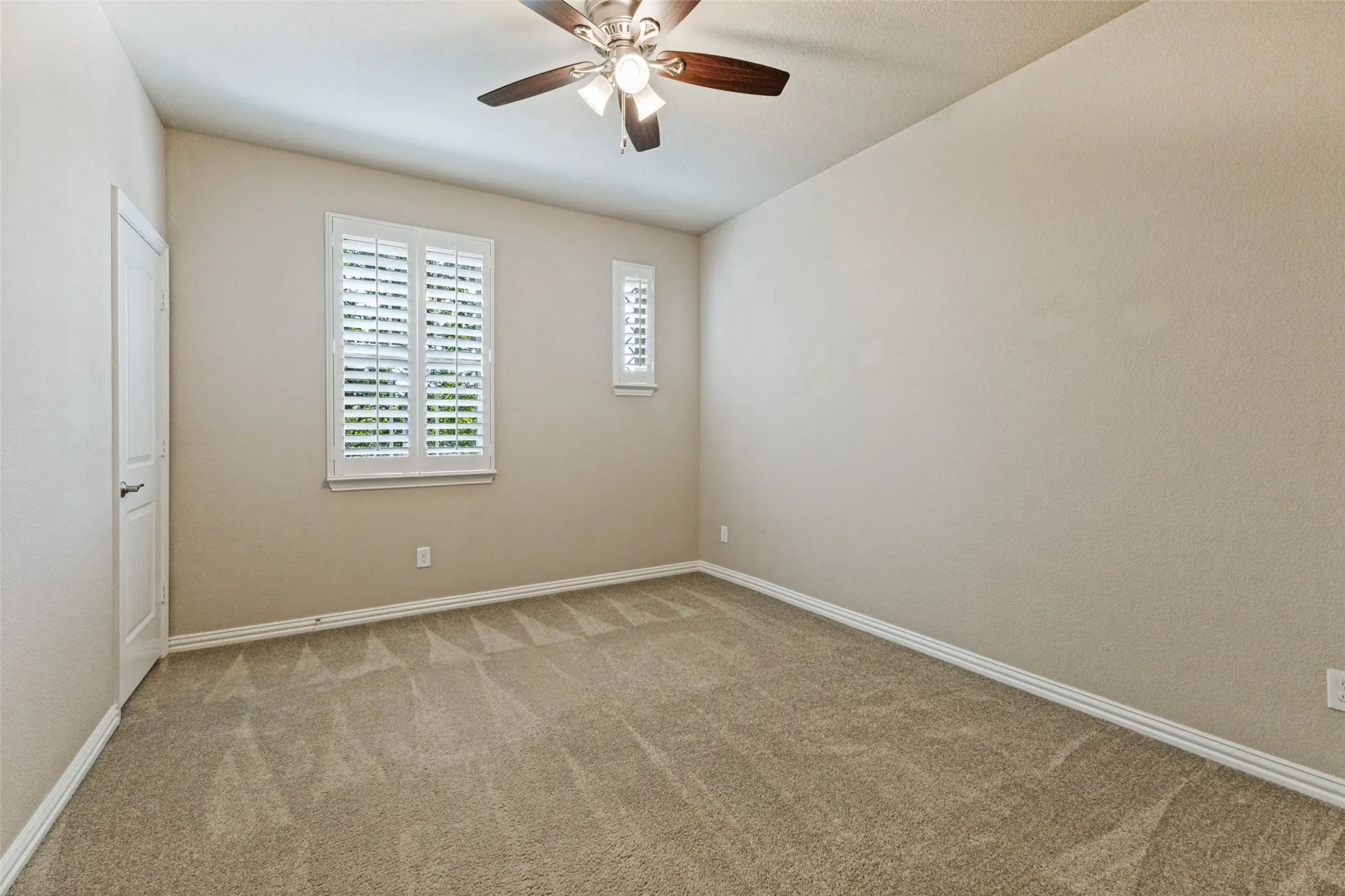 Upstairs bedroom with plantation shutters and a ceiling fan
