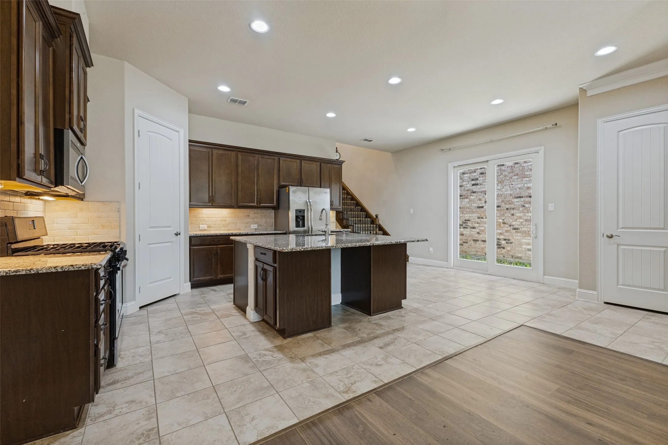 Kitchen featuring a central island, stainless steel appliances, and tile flooring open to living and dining space