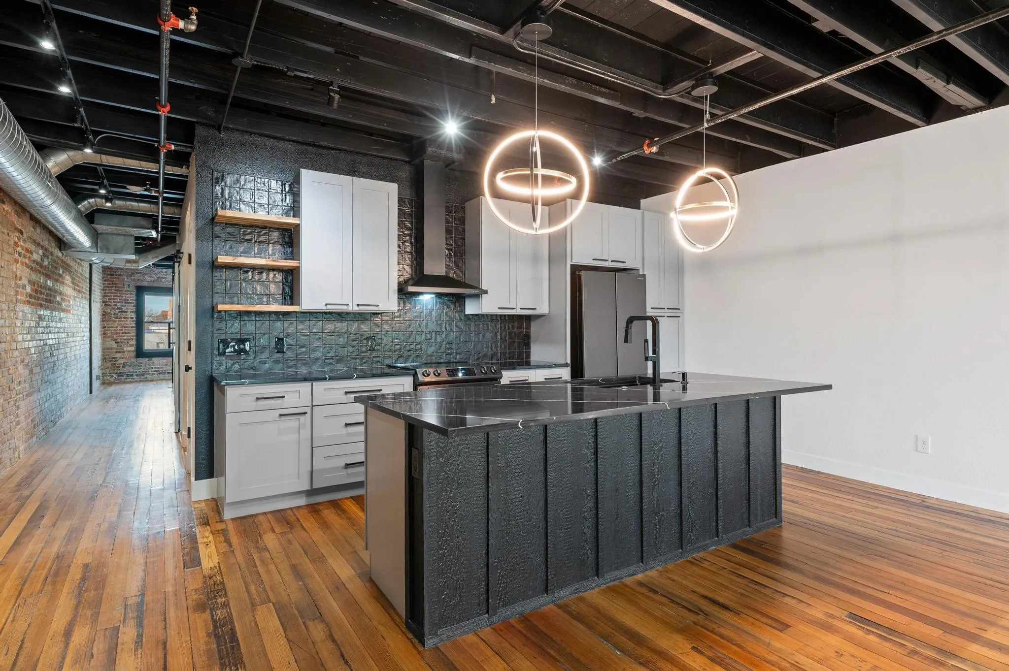 Modern kitchen featuring a large central island with a sink, light gray cabinetry, and dark countertops