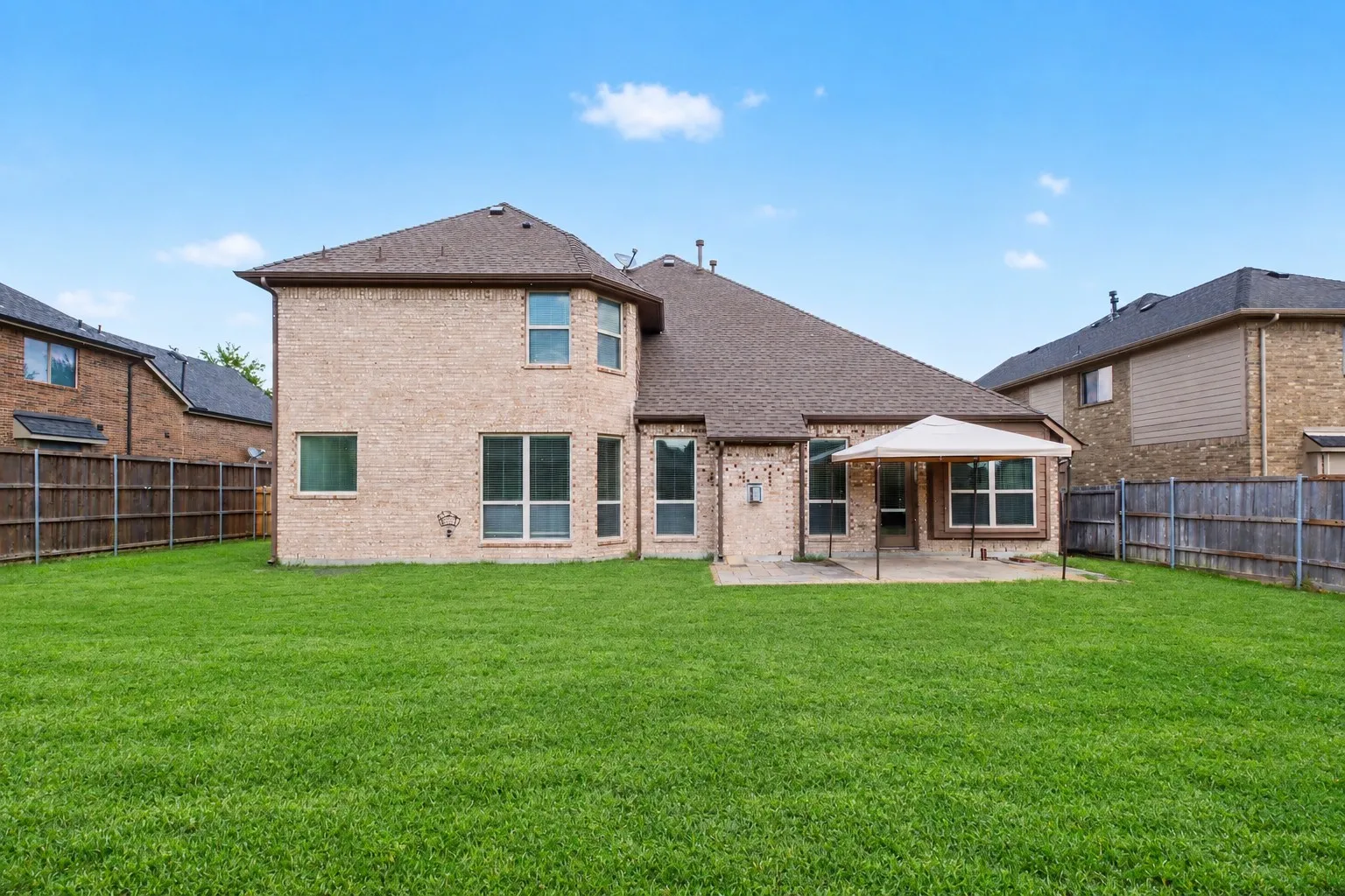 Brick exterior with a gabled roof, a rear patio, and a large grassy area