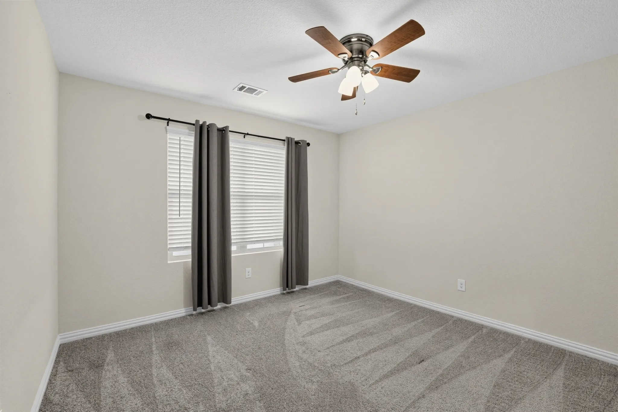 Neutral wall color, wall-to-wall carpeting, window with blinds, and a ceiling fan with integrated lighting