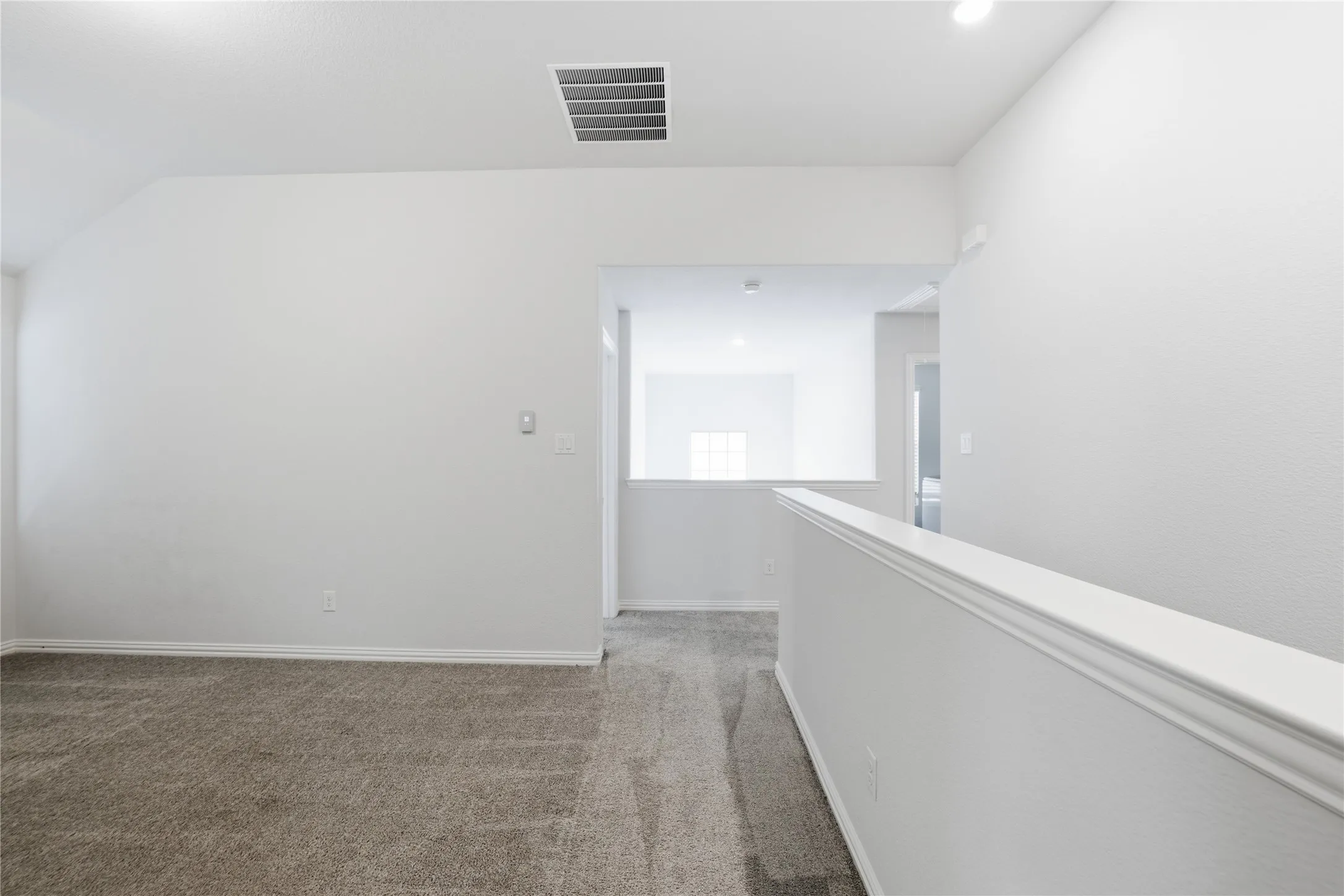 Carpeted landing featuring a half wall with railing, a wall cutout, and recessed lighting
