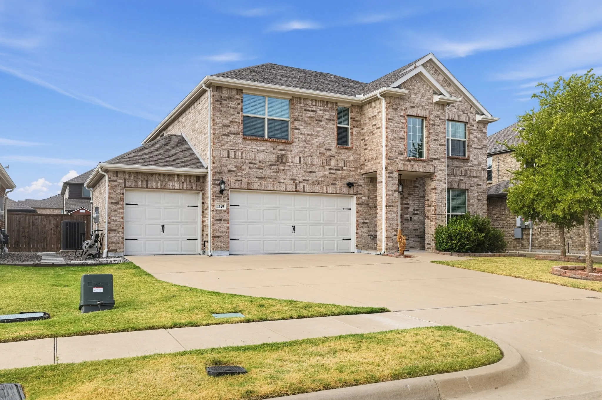 Two-story brick exterior with a two-car garage, concrete driveway, and front lawn landscaping
