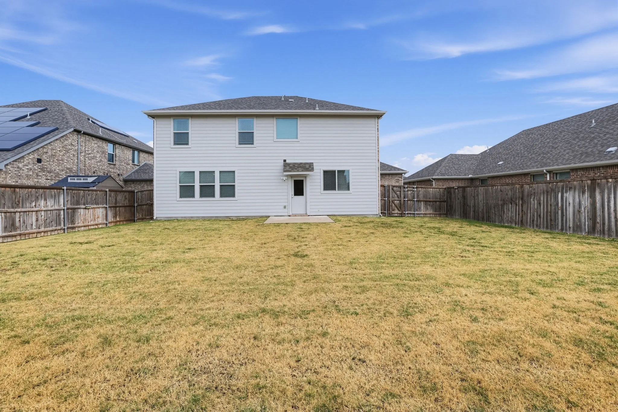 Expansive backyard featuring a privacy fence and concrete patio