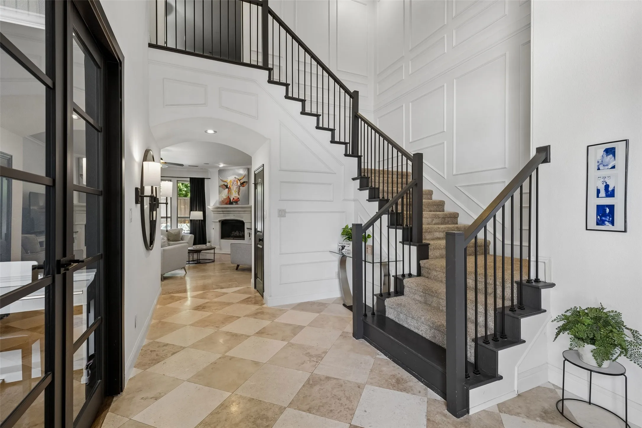 Spacious entry with soaring ceilings. Travertine floors and wood paneling walls.