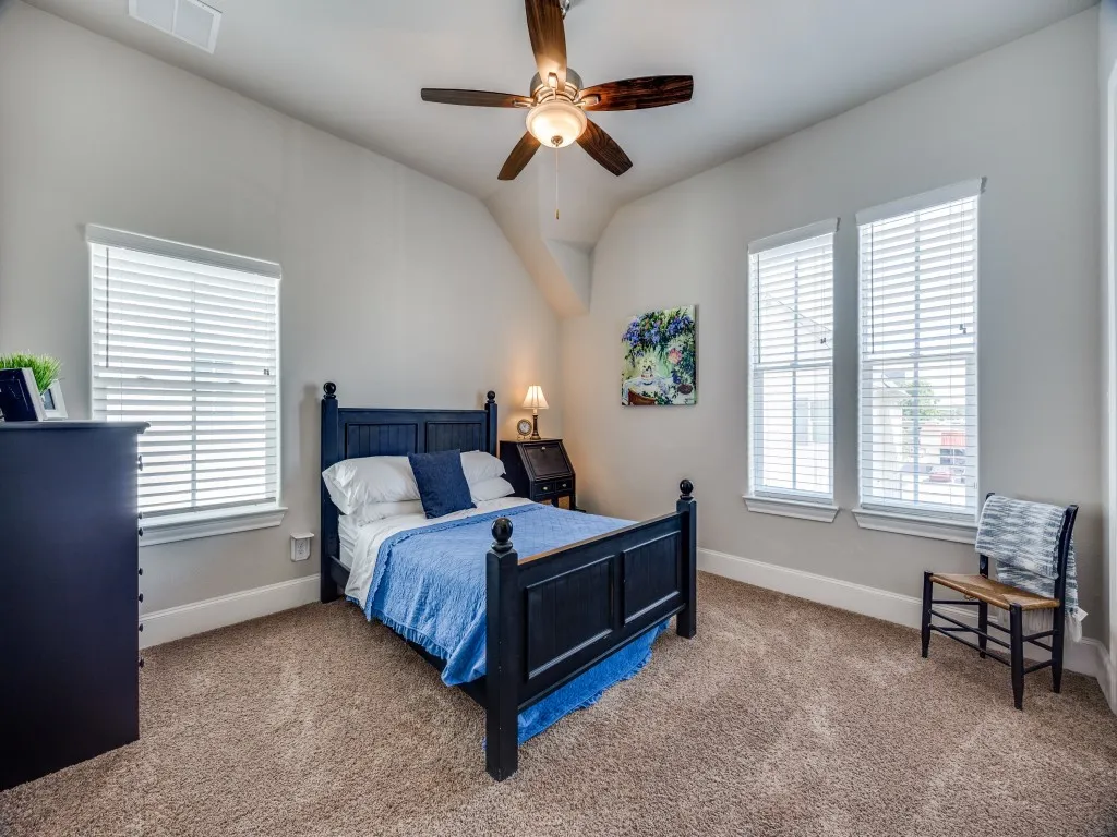 Vaulted ceiling with a ceiling fan, plush carpet flooring, and multiple windows with blinds