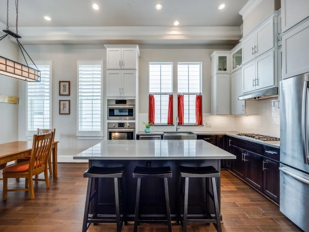 Kitchen featuring an island with countertop, stainless steel appliances, wood-finish flooring, white cabinetry, and recessed lighting