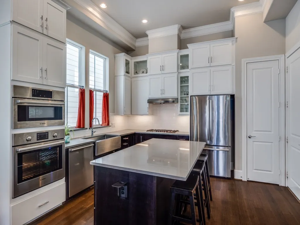 Stainless steel appliances, white shaker cabinetry, built-in double oven, deep farmhouse sink, and a contrasting island with seating