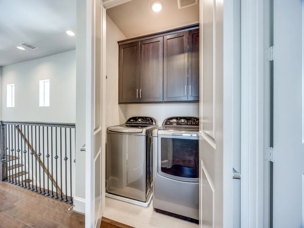 Integrated laundry area featuring built-in cabinetry, overhead lighting, and white panel doors