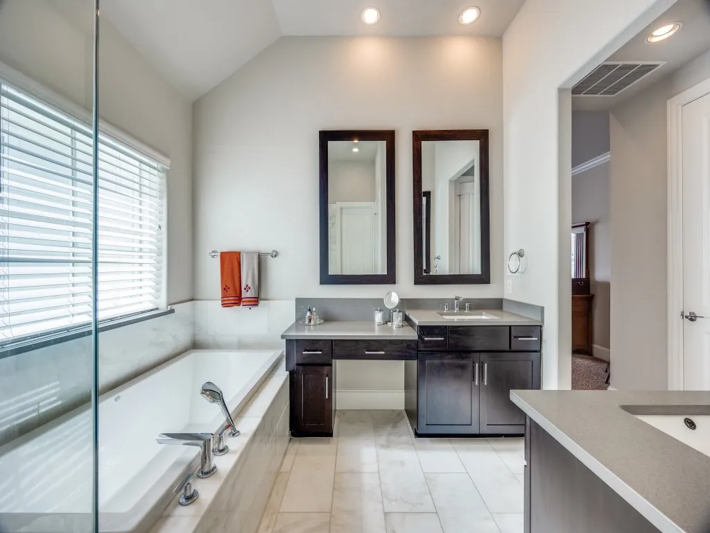 Dual dark wood vanities with integrated sinks, light-toned stone countertops, and recessed lighting