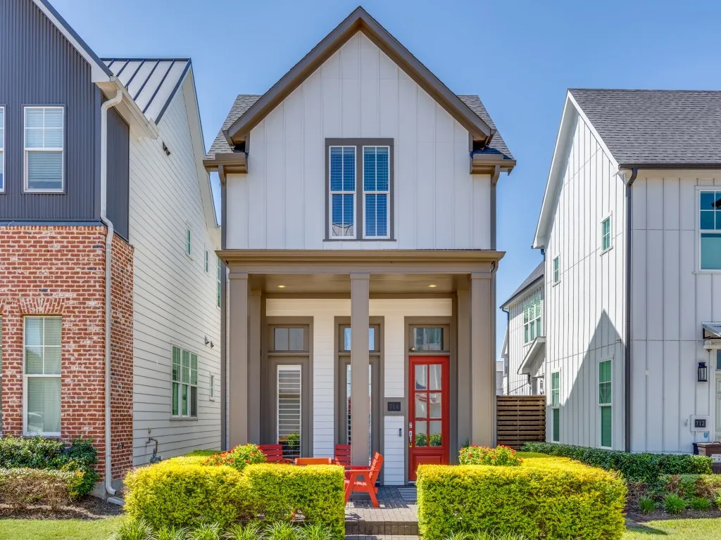 Modern farmhouse exterior featuring vertical board and batten siding, a covered entry porch with columns, and a vibrant red front door