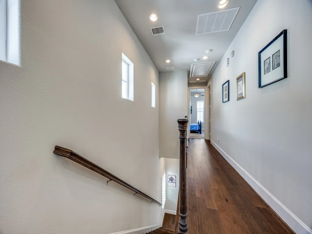 Hardwood flooring, recessed lighting, white baseboards, and a wood-finish handrail