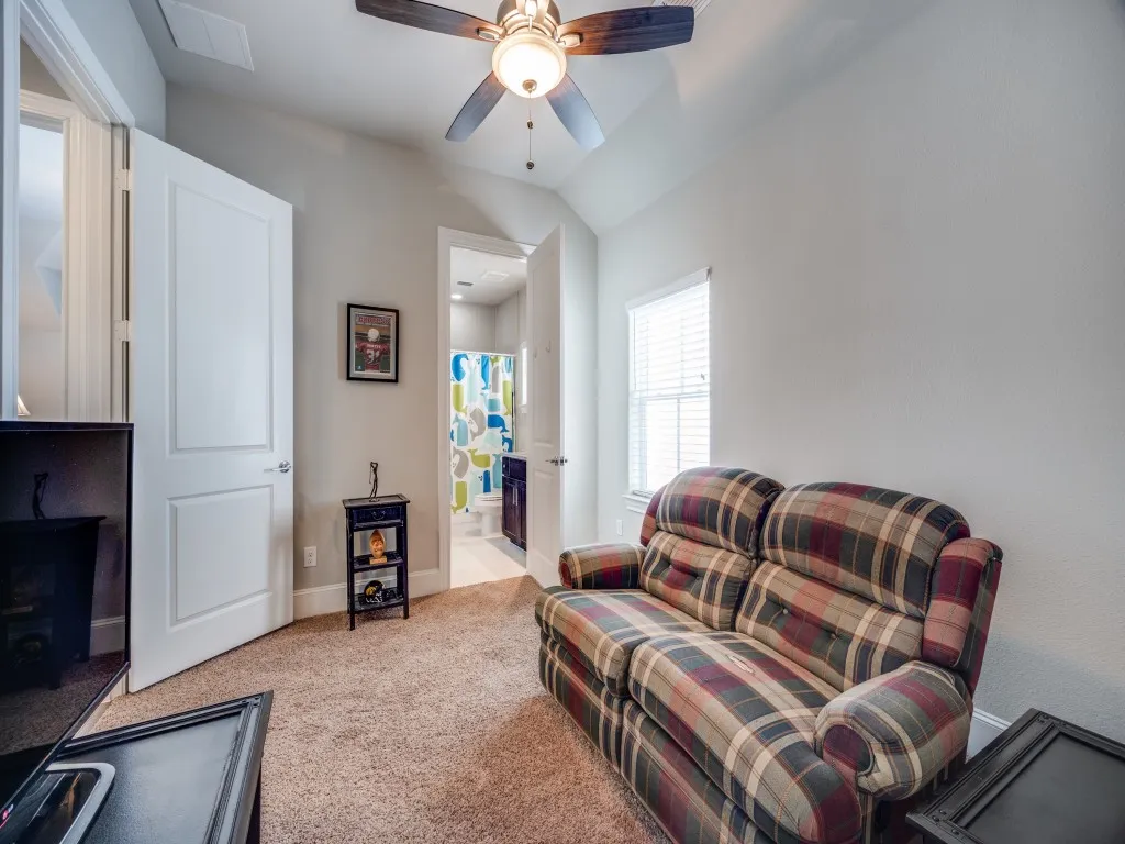 Vaulted ceiling with ceiling fan, light-colored walls, and carpet flooring