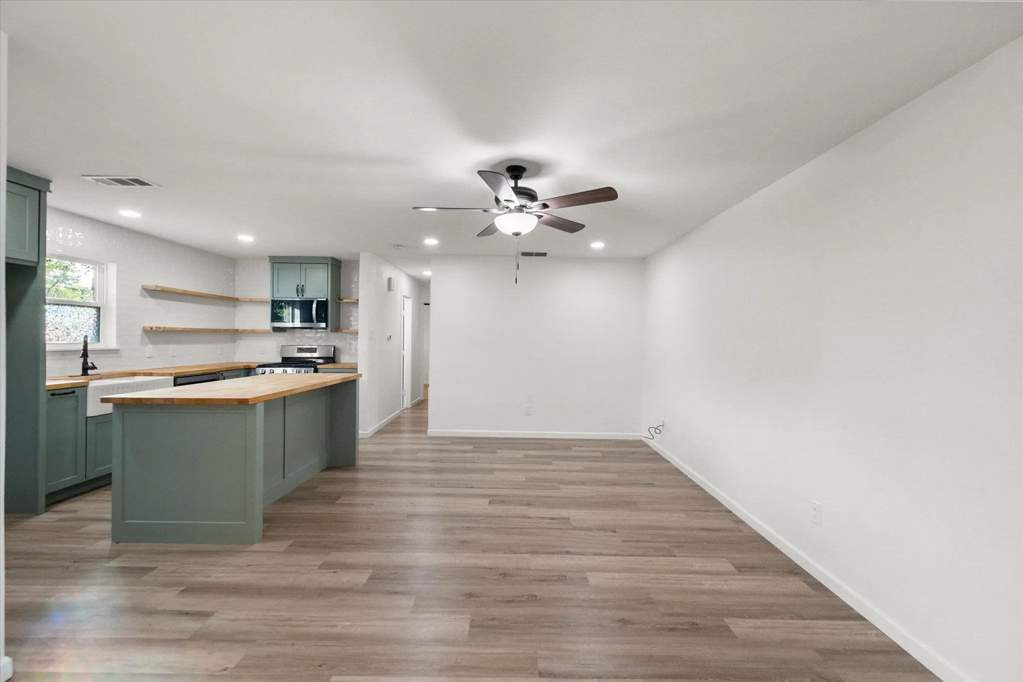 Open-concept living area with wood lookin ceramic flooring, a contemporary ceiling fan, and recessed LED lights
